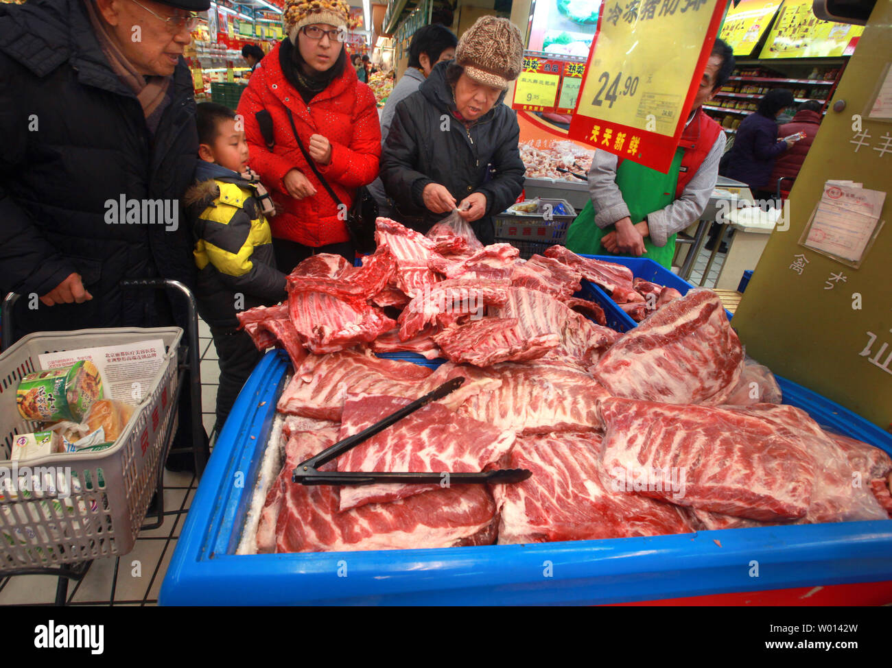 Chinesische Käufer überprüfen Sie heraus große Fächer von frischem Schweinefleisch auf Verkauf zu einem Lebensmittelgeschäft in Peking am 15. Januar 2014. Schweinefleisch Verbrauch in China auf dem Vormarsch aufgrund steigender Einkommen und Schweinefleisch Einfuhren aus den Vereinigten Staaten. Das chinesische Unternehmen Shuanghui International vor kurzem gekauft Virginia-based Smithfield. UPI/Stephen Rasierer. Stockfoto