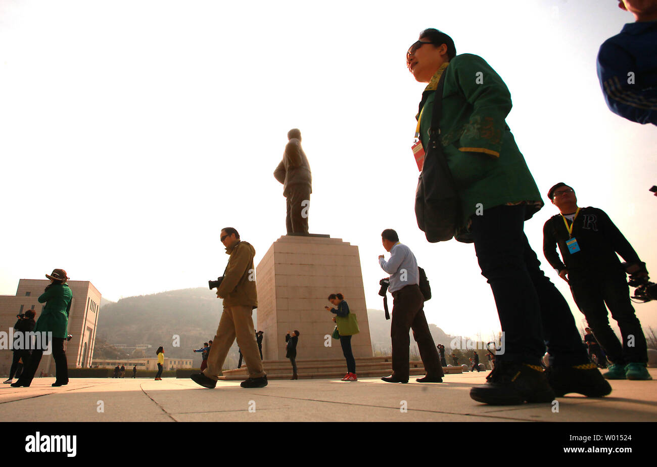 Chinesische vorbei durch eine große Statue von Chinas ehemaligen Steuermann Mao Zedong bei der Ankunft im Revolutionären Memorial Hall, präsentiert die Ereignisse, die zu der Entstehung der Volksrepublik China führte, in Yan'an, Provinz Shaanxi, am 6. April 2014. Yan'an war in der Nähe der Endpunkt der Langen Marsch, und wurde zum Zentrum der Chinesischen Kommunistischen Revolution führte meine Mao von 1936 bis 1948. Die chinesischen Kommunisten feiern die Stadt als Geburtsstätte des modernen China und der Kult von Mao. UPI/Stephen Rasierer Stockfoto