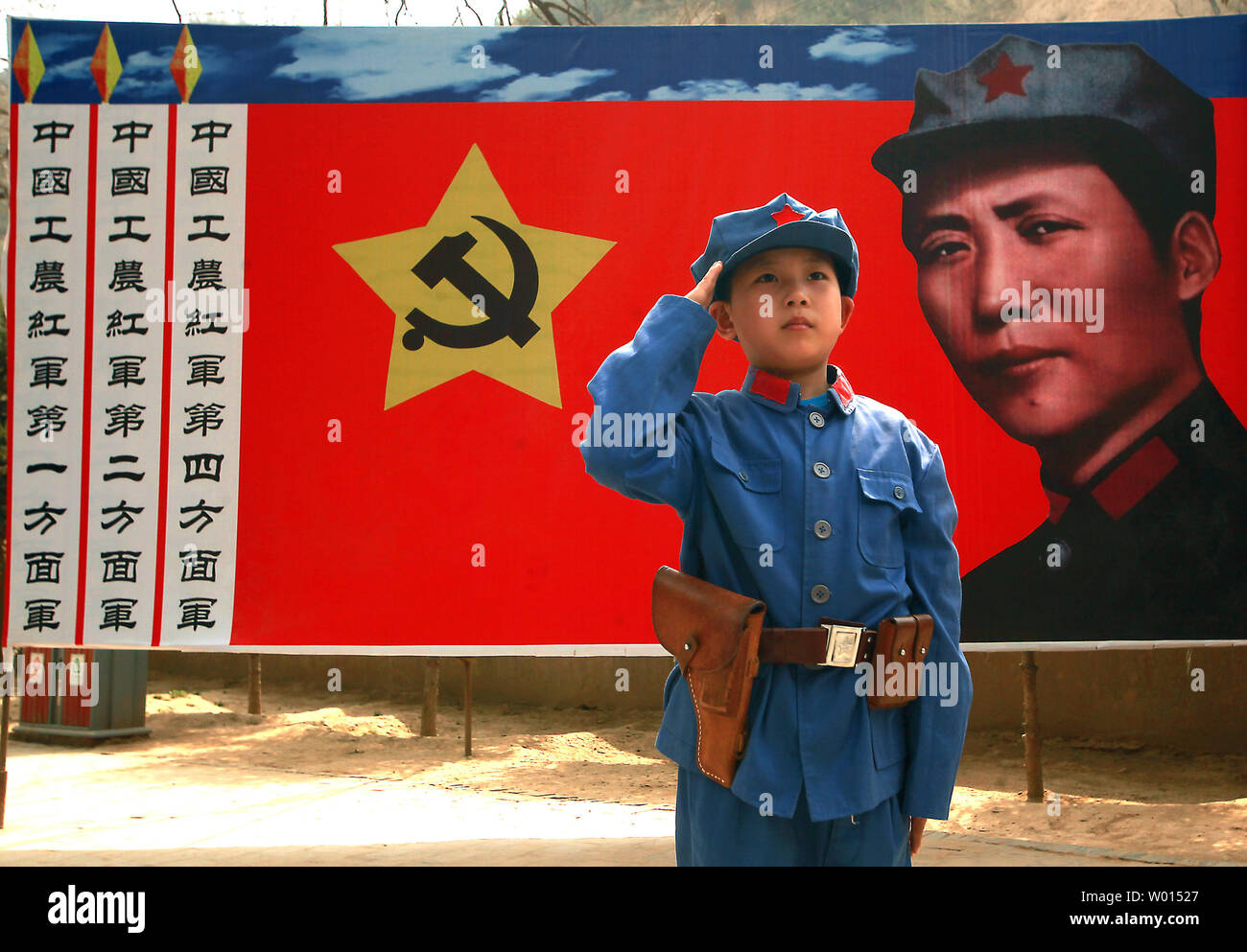 Ein chinesischer Junge in eine kommunistische Uniform gekleidet posiert für ein Foto vor einem Banner der ideale Soldat Li Feng der kommunistischen Partei, die an einem Standort durch ehemalige Steuermann Mao Zedong und anderen Führern verwendet Politik und zukünftige Strategien in der Yangjialing Revolution zu diskutieren, in Yan'an, Provinz Shaanxi, am 6. April 2014. Yan'an war in der Nähe der Endpunkt der Langen Marsch, und wurde zum Zentrum der Chinesischen Kommunistischen Revolution führte meine Mao von 1936 bis 1948. Die chinesischen Kommunisten feiern die Stadt als Geburtsstätte des modernen China und der Kult von Mao. UPI/Stephen Rasierer Stockfoto
