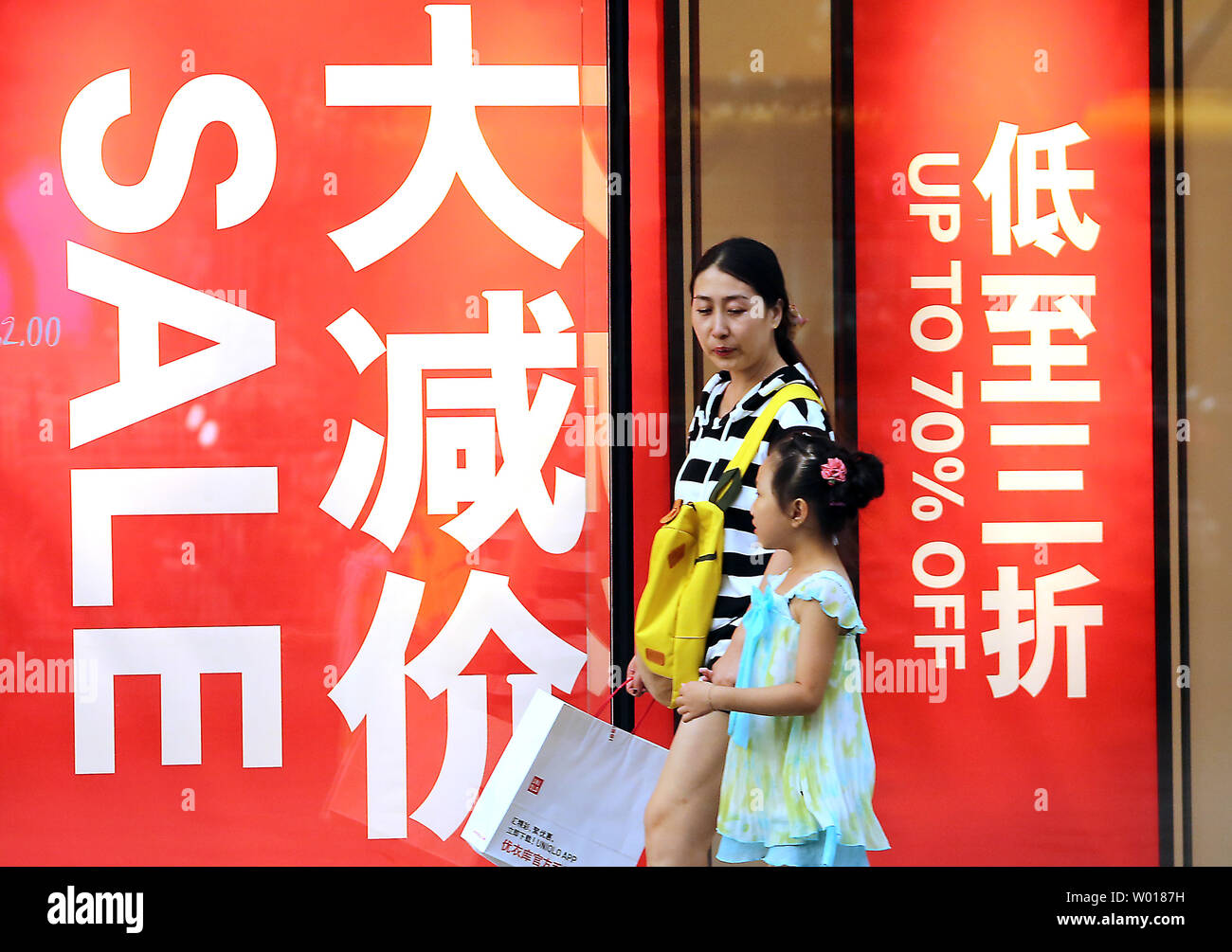 Chinesische Käufer vorbei an einem Bekleidungsgeschäft Werbung grosse Verkäufe an einem Mall in Peking am 27. Juli 2015. China kämpft nun mit den Folgen einer ernsthaft überbewertet Börse, chronische über Investitionen und die Voraussetzungen eines schädlichen Immobilienblase zu beschäftigen. Foto von Stephen Rasierer/UPI Stockfoto