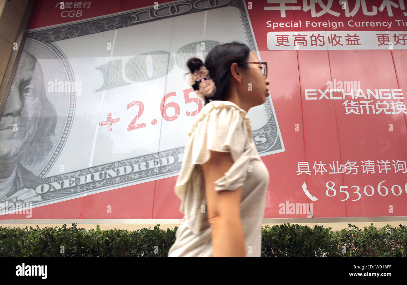 Chinesische Spaziergang, vorbei an einer Bank Werbung seiner Exchange Index auf dem US-Dollar, in Peking am 22. August 2015. Chinas belagerte Börse tanked um mehr als 4 Prozent am Freitag, wobei wöchentliche Verluste für die wichtigsten Indizes zu fast 12 Prozent und die Zweifel über die Fähigkeit, eine andere Peking Anfall von Panik zu verkaufen, da der Markt zu verhindern Zusammenbruch wieder näherte. Foto von Stephen Rasierer/UPI Stockfoto