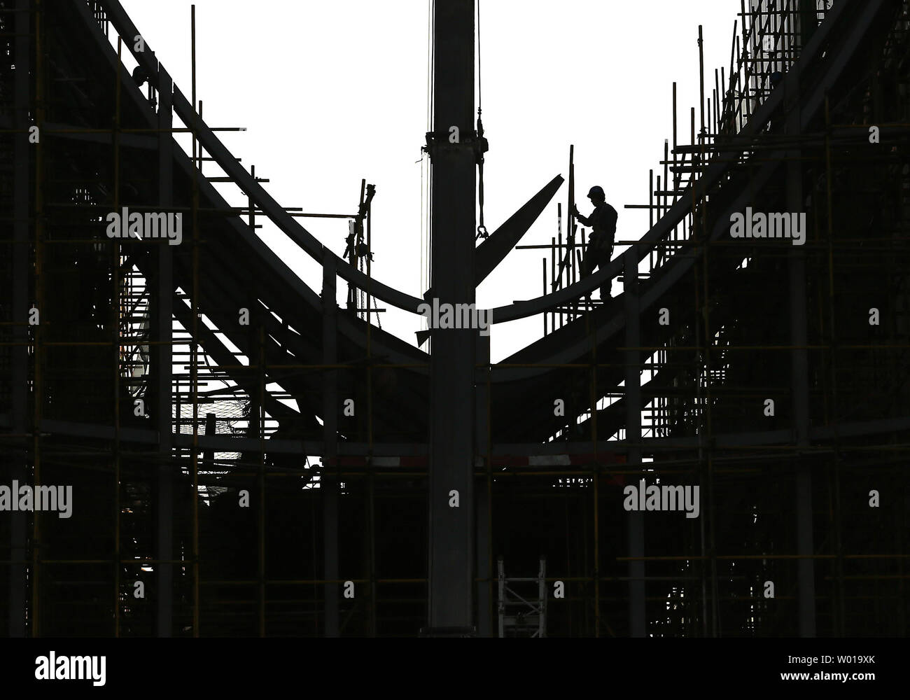 Eine chinesische Bauarbeiter wartet auf Teile eines Gebäudes auf einem neuen kommerziellen Komplex im Bau in Peking am 5. Januar 2016 gesenkt werden. Chinas wichtigsten Börsen Tanked am ersten Handelstag des Jahres am Montag, Auslösen einer 'Leistungsschalter', das nicht mehr Aktien Handel Bundesweite. China gekämpft, wackelige Gefühl ein Tag zum Ufer nach der Aktienindizes und Yuan Währung stolperten, klappern Märkte weltweit. Foto von Stephen Rasierer/UPI Stockfoto