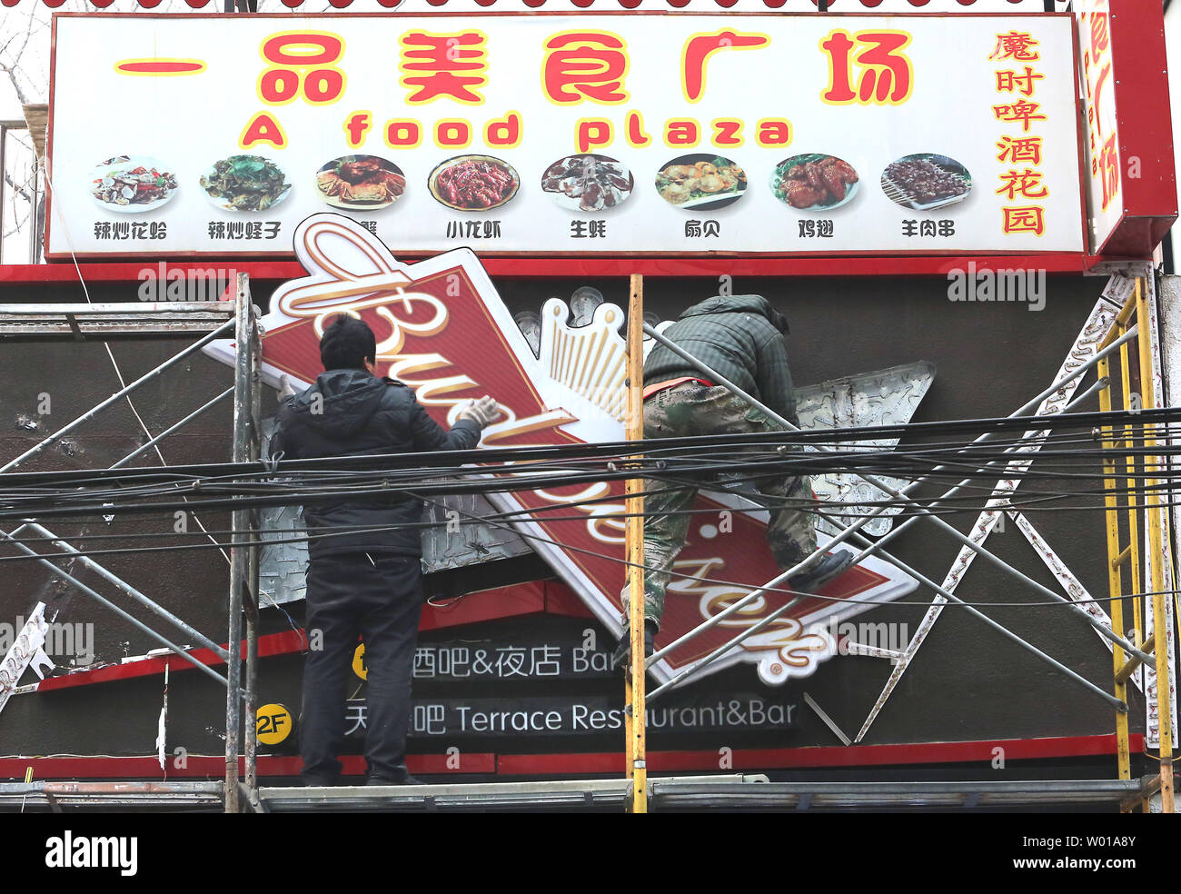 Chinesische Arbeiter ein Budweiser Zeichen außerhalb ein Restaurant in Peking am 15. Februar 2016. Ungleichgewichte im Außenhandel mit China, sowie der Schutz der Rechte des geistigen Eigentums, sind wesentliche Aspekte, die in der US-Präsidentschaftswahl geworden. Foto von Stephen Rasierer/UPI Stockfoto