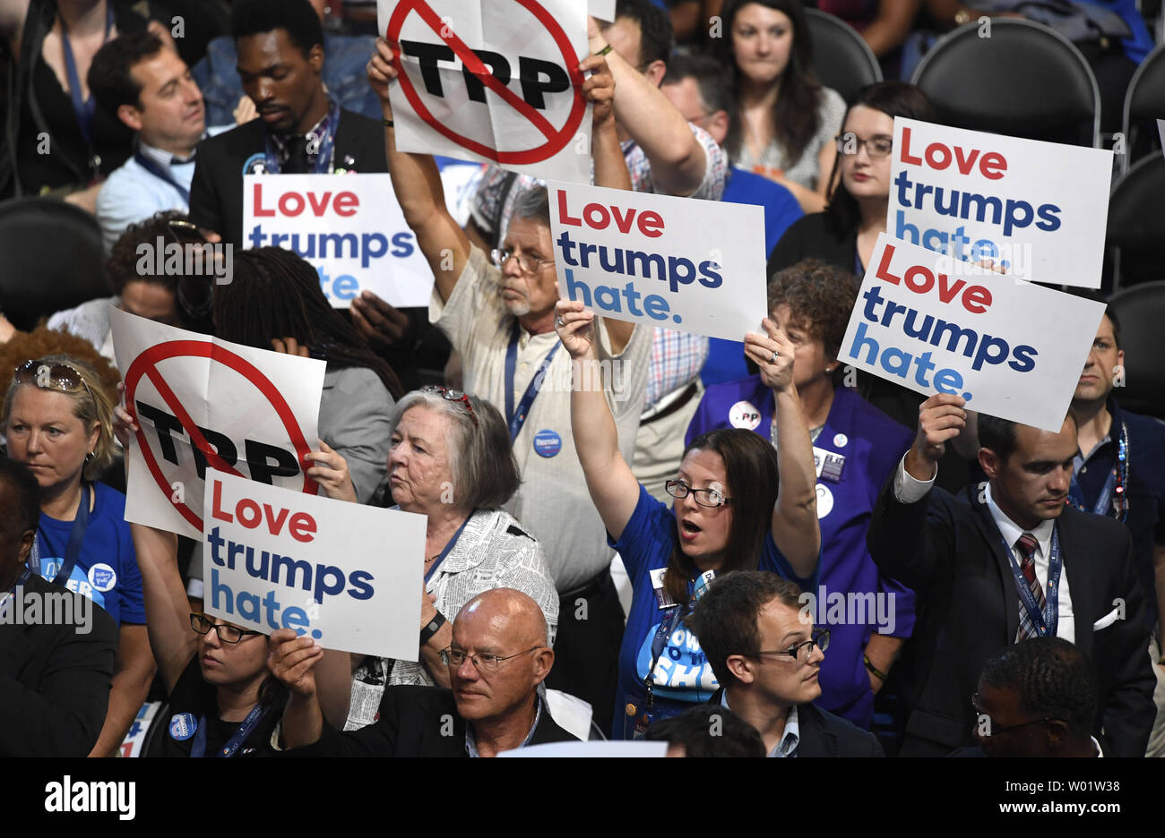 Delegierte aus Arkansas Hold up Anti-Donald Trump Zeichen wie ein anderer hält ein Zeichen gegen den TPP, Transpazifische Partnerschaft Handelsabkommen, bei der Democratic National Convention 2016, bei Wells Fargo Center in Philadelphia, Pennsylvania am 25. Juli 2016. Die Delegierten die Nominierung von Hillary Clinton und Tim Kaine als demokratische Ticket für die Wahl im November bestätigen. Foto von Mike Theiler/UPI Stockfoto