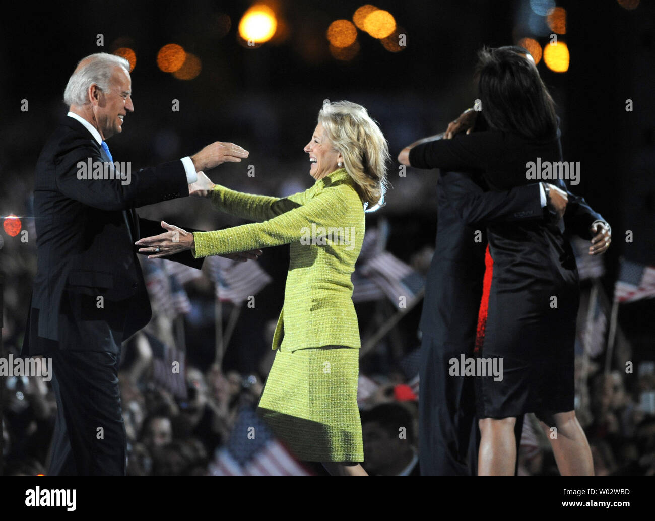 Präsident Barack Obama umarmt seine Frau Michelle als Vice Presient - wählen Sie Joe Biden (L) wird von seiner Frau Jill vor einem riesigen Publikum bei seiner Wahl nacht Rallye im Grant Park in Chicago am 4. November 2008 begrüßt. Der Demokrat Obama besiegt der Republikaner John McCain. Mehr als 200.000 Menschen nahmen an der Kundgebung und Feier. (UPI Foto/Pat Benic) Stockfoto