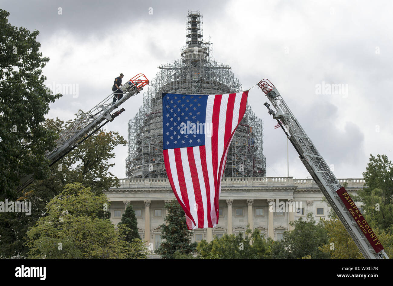 Ein Feuerwehrmann hilft eine amerikanische Flagge in der Nähe des U.S. Capitol Gebäude, zu Ehren der gefallenen Kämpfer Kämpfer, in Washington, D.C. am 30. September 2015. Dieses Wochenende ist der 34. jährlichen Nationalen gefallene Feuerwehrmänner Memorial Wochenende wo gefallene Feuerwehrmänner bei der nationalen Gedenkstätte in Maryland geehrt werden. Foto von Kevin Dietsch/UPI Stockfoto