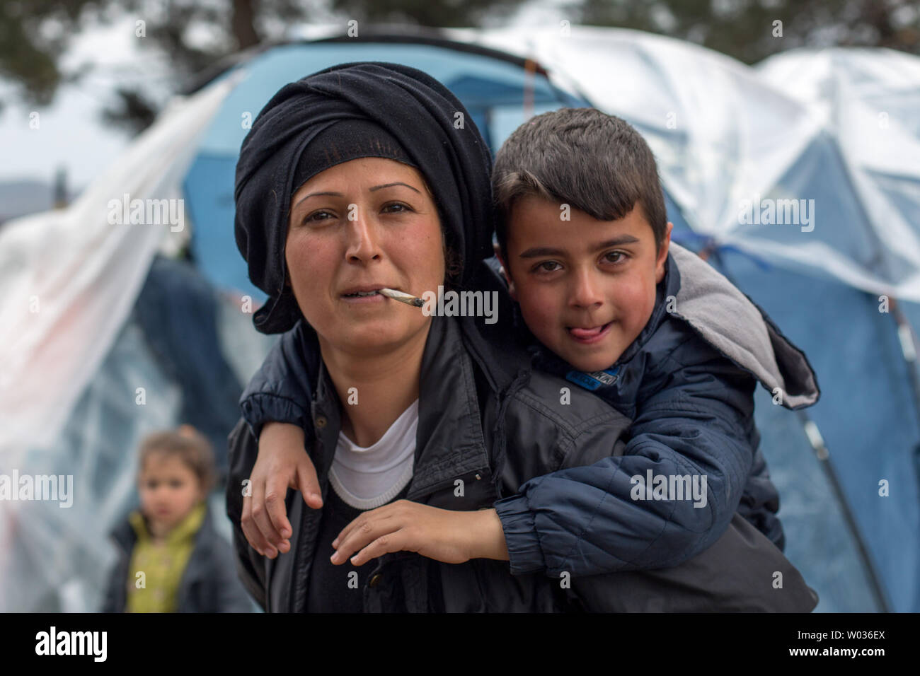 Mawleda Aisho trägt eine ihrer Kinder auf den Rücken, als sie sich ihren  Weg durch ein behelfsmäßiges Lager in Idomeni, Griechenland, an der Grenze  zu Mazedonien, im April 2016, nach der Grenze