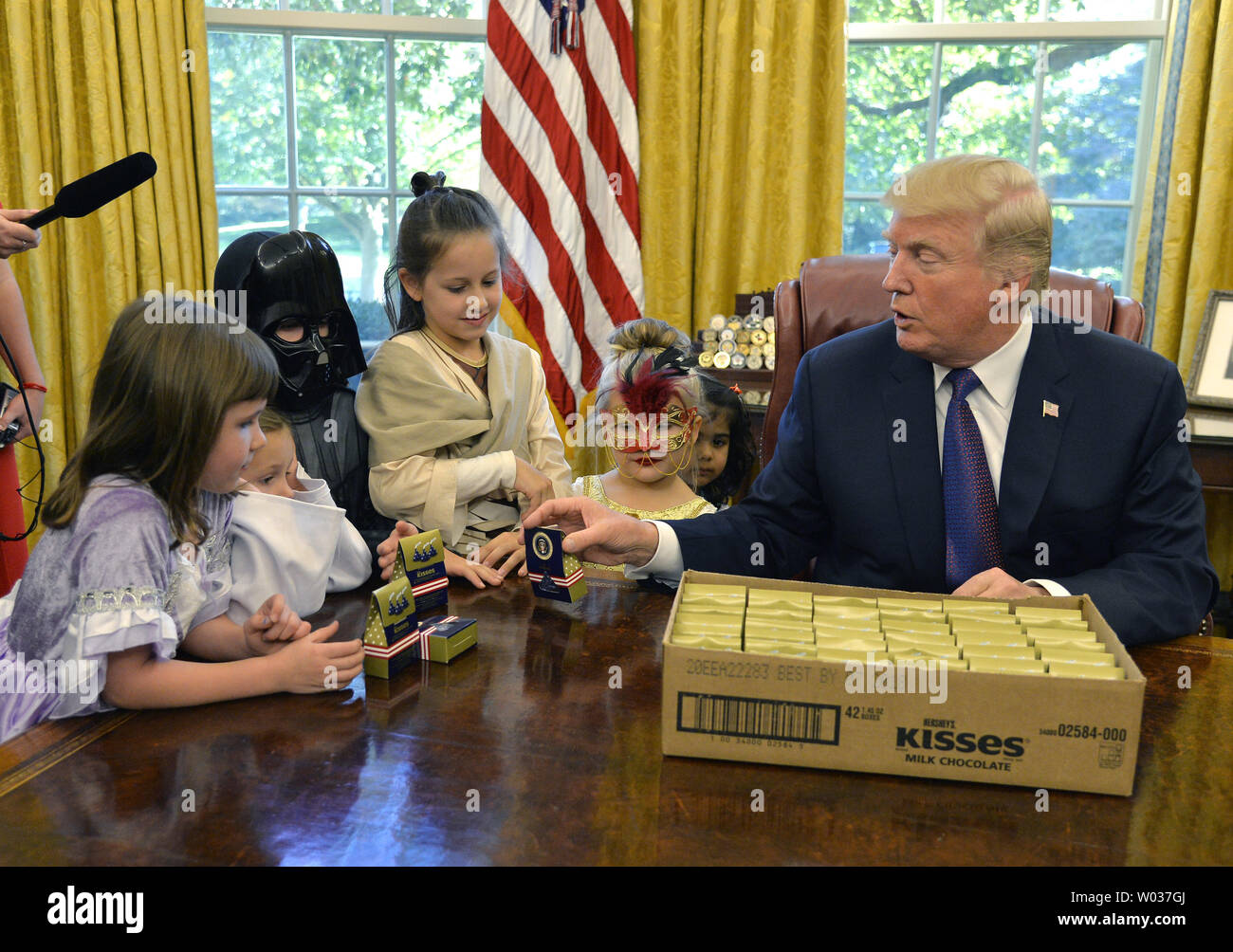 Präsident Donald Trump heraus gibt, Süßigkeit mit dem Presidential Seal als er Kinder in Halloween Kostüme, die im Oval Office des Weißen Hauses, Oktober 27, 2017, in Washington, D.C., Trumpf und die erste Dame Melania Trump begrüßt werden Kinder der militärischen Herzlich willkommen in der White House nächste Woche für Halloween Trick - oder - behandeln. Foto von Mike Theiler/UPI Stockfoto