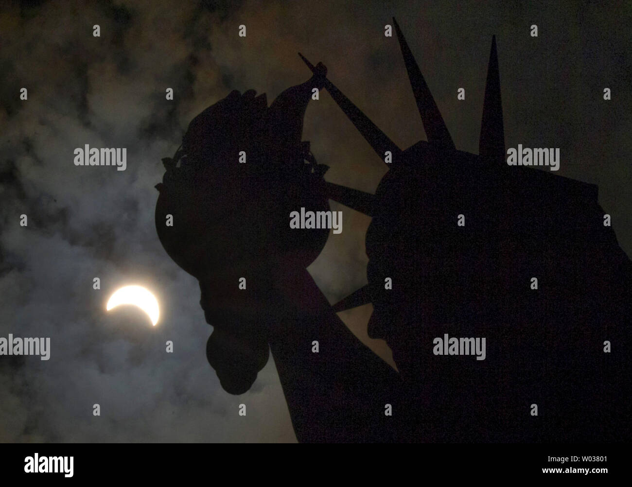 Eine partielle Sonnenfinsternis bewegt sich über den Himmel in der Nähe der Krone und der Fackel der Freiheitsstatue auf Liberty Island am 21. August 2017 in New York City. Heute ist die lange erwartete Sonnenfinsternis verdunkelte sich der Himmel von Oregon nach South Carolina wie der Mond zwischen Erde und Sonne. Das letzte Mal die aneinandergrenzenden Staaten der USA sah eine totale Sonnenfinsternis 1979 war, und der nächste wird nicht bis 2024. Foto von John angelillo/UPI Stockfoto