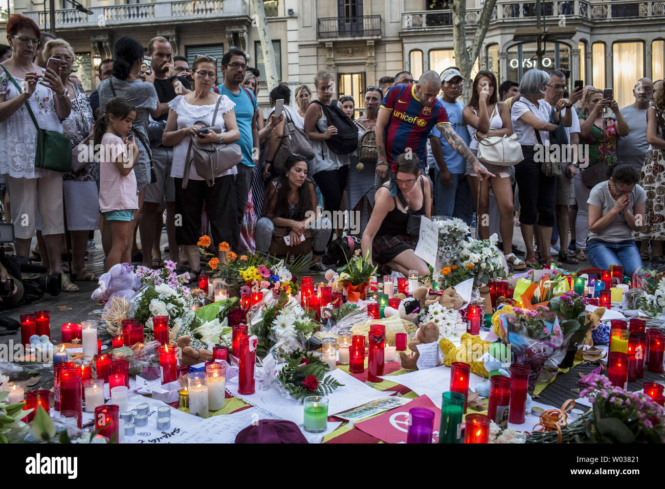 Menschen stehen neben Blumen, Kerzen und andere Gegenstände auf die Font de Canaletes in Barcelona, als Sie erinnert an die Opfer des Barcelona Terroranschlag bezahlen, einen Tag nach dem van in die Menge gepflügt, tötete 14 Menschen und über 100 wurden verletzt, am 18. August 2017. Foto von Angel Garcia/UPI Stockfoto