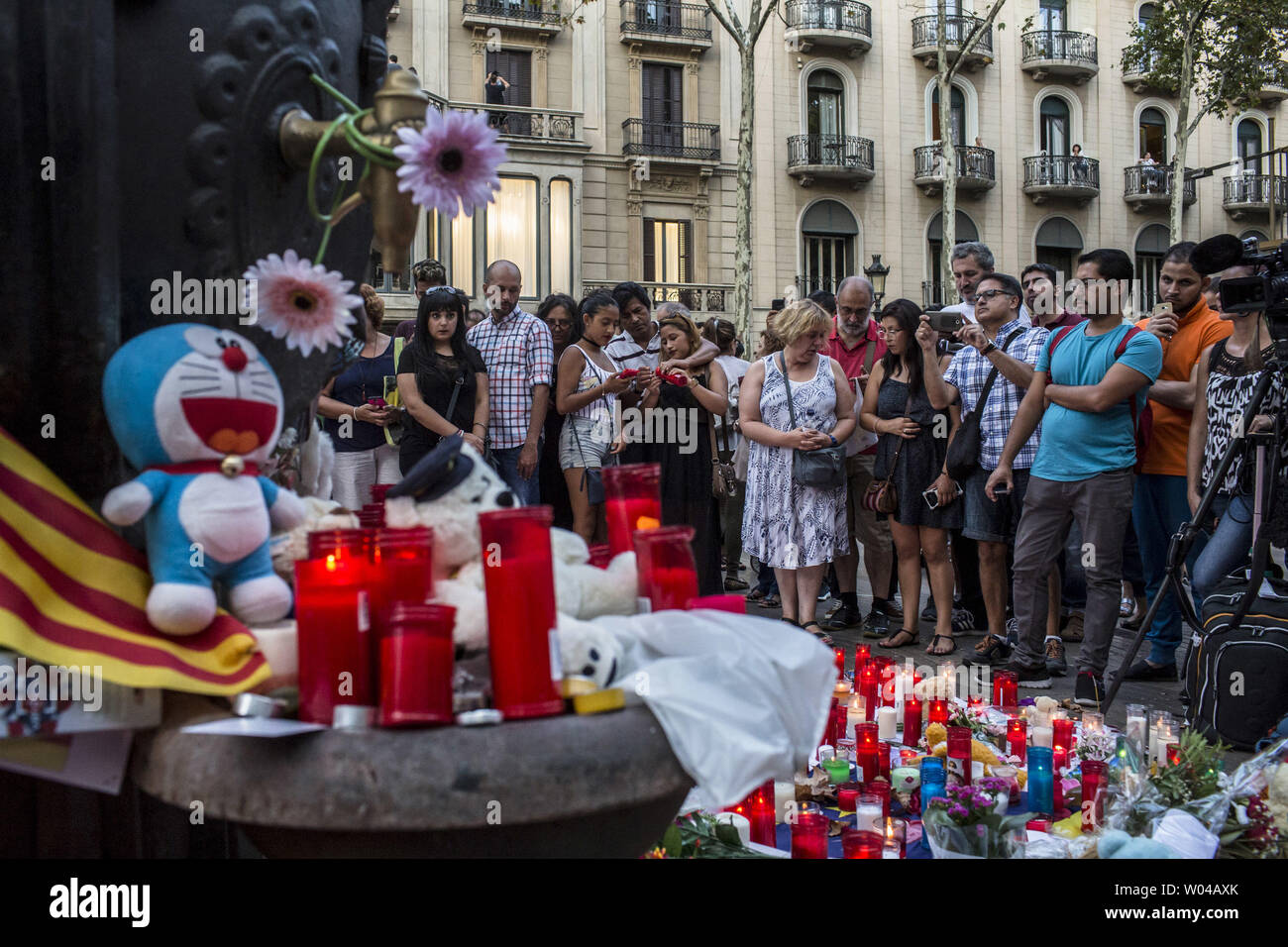 Menschen stehen neben Blumen, Kerzen und andere Gegenstände auf die Font de Canaletes in Barcelona, als Sie erinnert an die Opfer des Barcelona angriff, einen Tag nach dem van in die Menge gepflügt, 14 Personen getötet und über 100 verletzt wurden am 18. August 2017. Die Fahrer haben am 17. August 2017 gepflügt. Foto von Angel Garcia/UPI Stockfoto