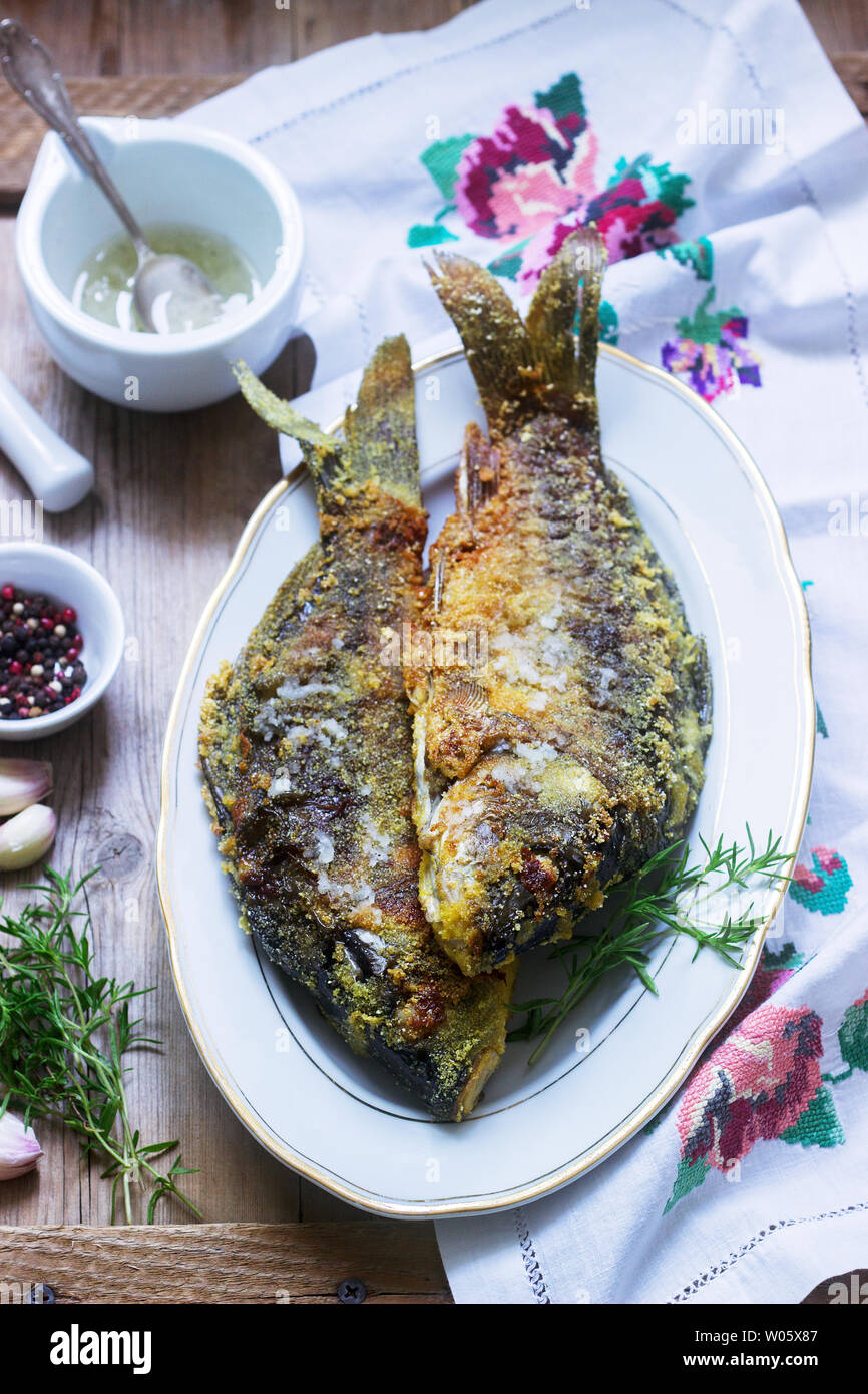 Traditionelle Moldauischen oder rumänischen Gericht, gebratener Fisch im Mais vor dem Panieren mit Knoblauch Sauce serviert. Rustikaler Stil, selektiven Fokus. Stockfoto