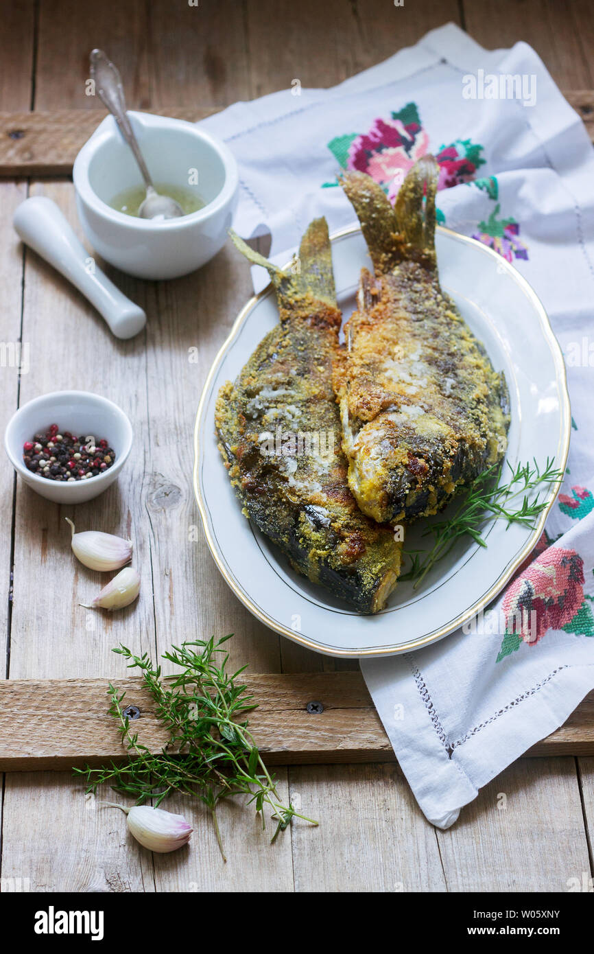 Traditionelle Moldauischen oder rumänischen Gericht, gebratener Fisch im Mais vor dem Panieren mit Knoblauch Sauce serviert. Rustikaler Stil, selektiven Fokus. Stockfoto