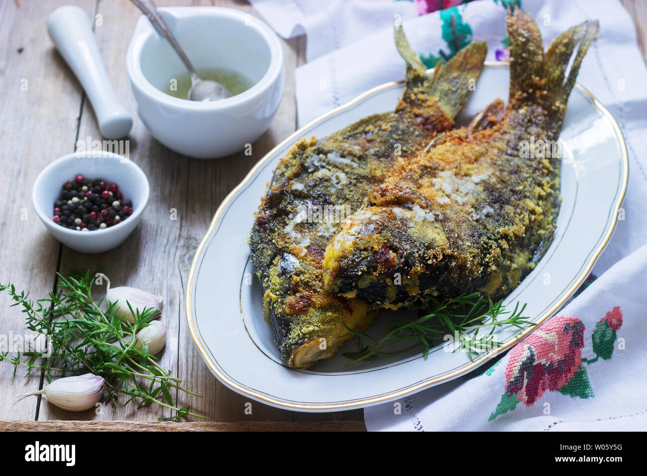 Traditionelle Moldauischen oder rumänischen Gericht, gebratener Fisch im Mais vor dem Panieren mit Knoblauch Sauce serviert. Rustikaler Stil, selektiven Fokus. Stockfoto