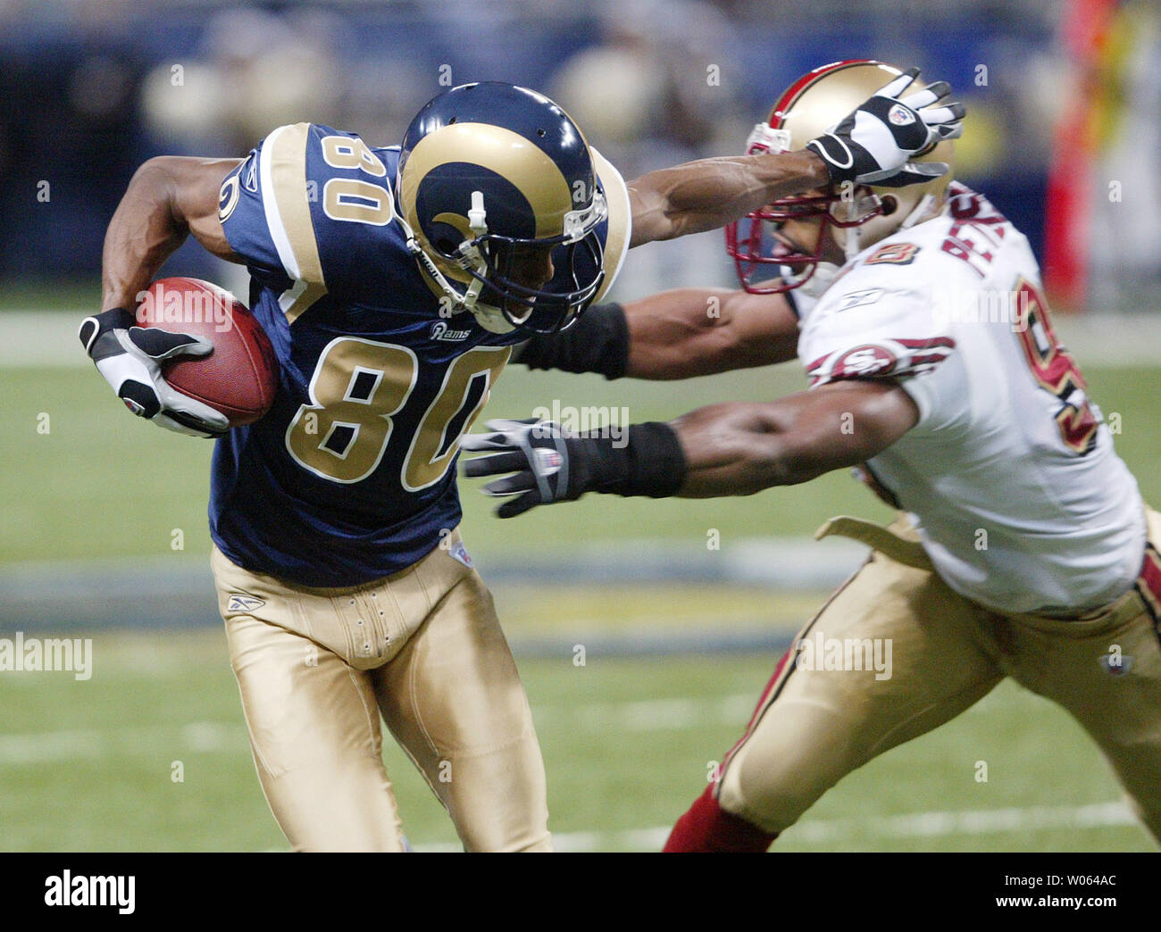 St. Louis Rams Isaac Bruce (80) schiebt San Francisco 49ers Julian Peterson weg nach einem Empfang und 7-Yard-Run Run im ersten Viertel an der Edward Jones Dome in St. Louis am 24. Dezember 2005. San Francisco gewann das Spiel, 24-20. (UPI Foto/Rechnung Greenblatt) Stockfoto