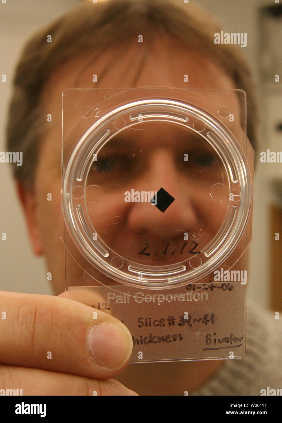 Frank Stadermann, Ph.D., Senior Research Scientist in der Abteilung für Physik an der Washington Universität zeigt einen Behälter mit drei Schichten eines kometarer Staubpartikel während der NASA sieben gesammelt - Jahr 2,88 Milliarden Kilometer Roundtrip Stardust Mission kometaren und interstellaren Staubteilchen zu sammeln, in der St. Louis am 9. Februar 2006. Stadermann, der auch Berater in der Stardust Mission, ging zum Johnson Space Center der NASA in Houston, Zeuge der Eröffnung am 17. Januar des wiederhergestellten Stardust probe Kanister, 15. Januar in Utah gelandet. Die Probe Kanister gefangen gehalten ein Fach, Pa Stockfoto