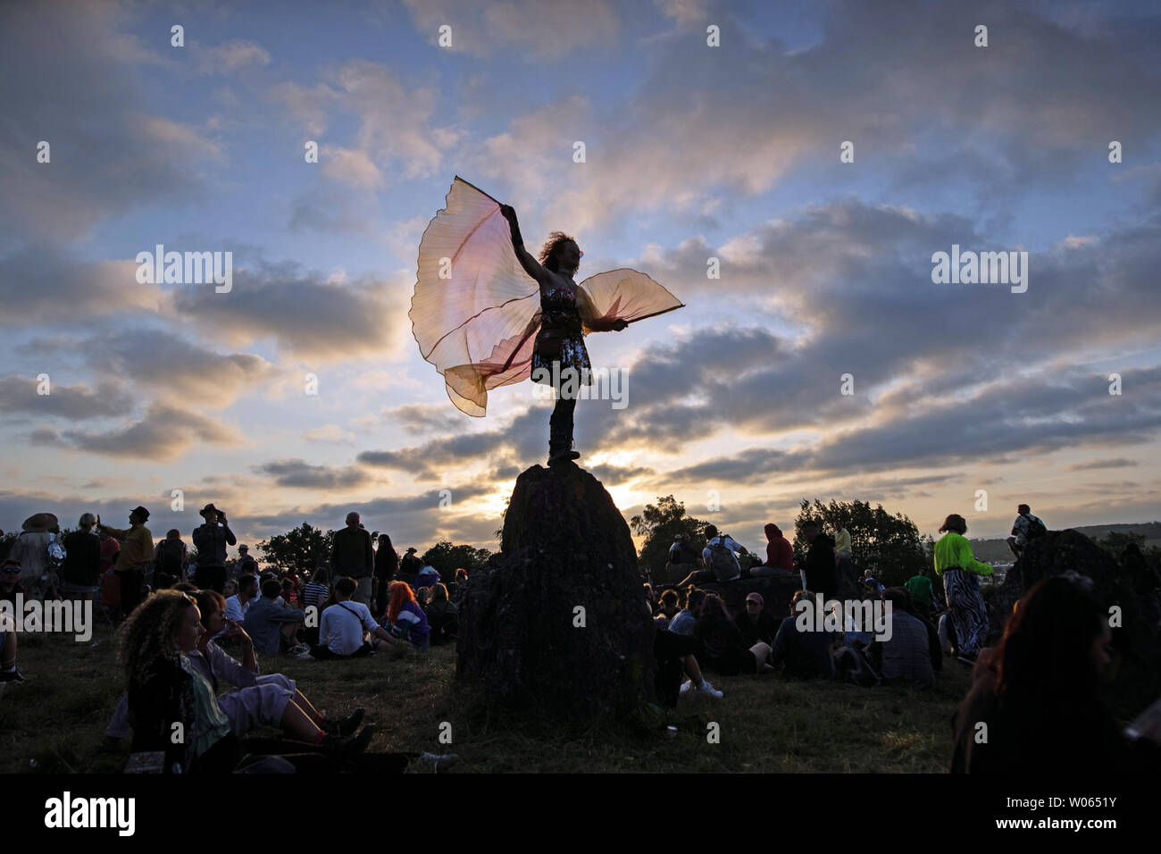 Ein Festival - goer Tänze bei Sonnenuntergang an der steinernen Kreis während des Glastonbury Festival würdig Bauernhof in Somerset. Stockfoto