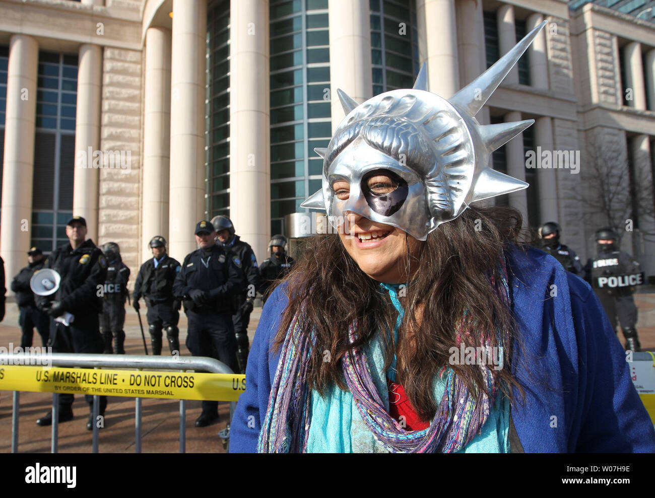 Eine Demonstrantin trägt eine Freiheitsstatue Maske Gesänge während Federal Marshalls in Kampfausrüstung stand Guard vor der Eagleton Bundesgericht in St. Louis am 12. Dezember 2014. Die Demonstranten marschierten zu mehreren Standorten einschließlich Rathaus, wo die Polizei das Gebäude gesperrt und hielten Demonstranten aus der Eingabe. Die Proteste werden auf die Ereignisse in Ferguson, Missouri. UPI/Rechnung Greenblatt Stockfoto