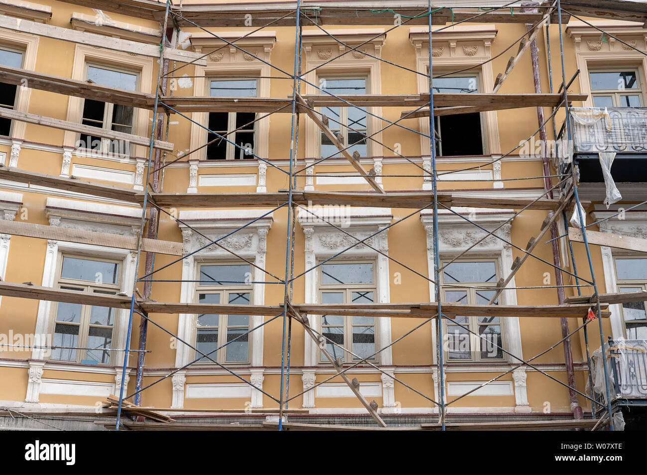 Gerüst am Haus, Renovierung. Gerüst am Gebäude, beige Wand und Fenster.  Gerüstsystem im Bau Stockfotografie - Alamy