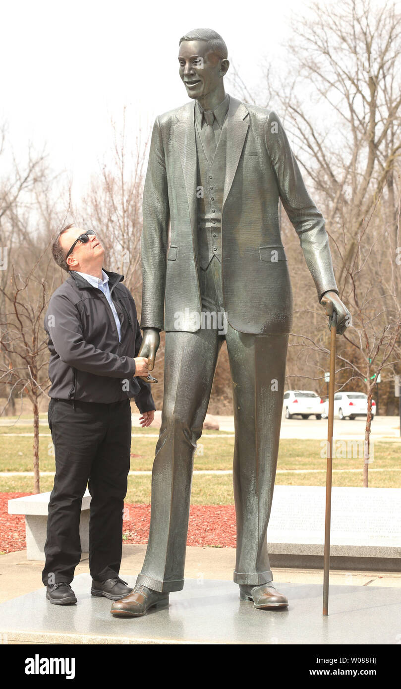 Ein Besucher der lebensgroße Statue von Robert Pershing Wadlow vergleicht seine Größe der "Alton Giant" in einem Park in Alton, Illinois am 23. März 2019. Wadlow, die in Alton, Illinois 1918 geboren war, gemessen 8 ft 11.1 Zoll und wurde als der größte Mensch, der je bei seinem Tod im Jahre 1940 lebte, im Alter von 22 Jahren bekannt. Watlow, der 439 Pfund wog, wurde zu einer Berühmtheit, nachdem seine US-Tour 1936 mit dem Ringling Brothers Circus, schließlich Arbeiten für die International Shoe Company, der seine 37AA Schuhgröße zu ihm kostenlos zur Verfügung gestellt. Foto von Bill Greenblatt/UPI Stockfoto