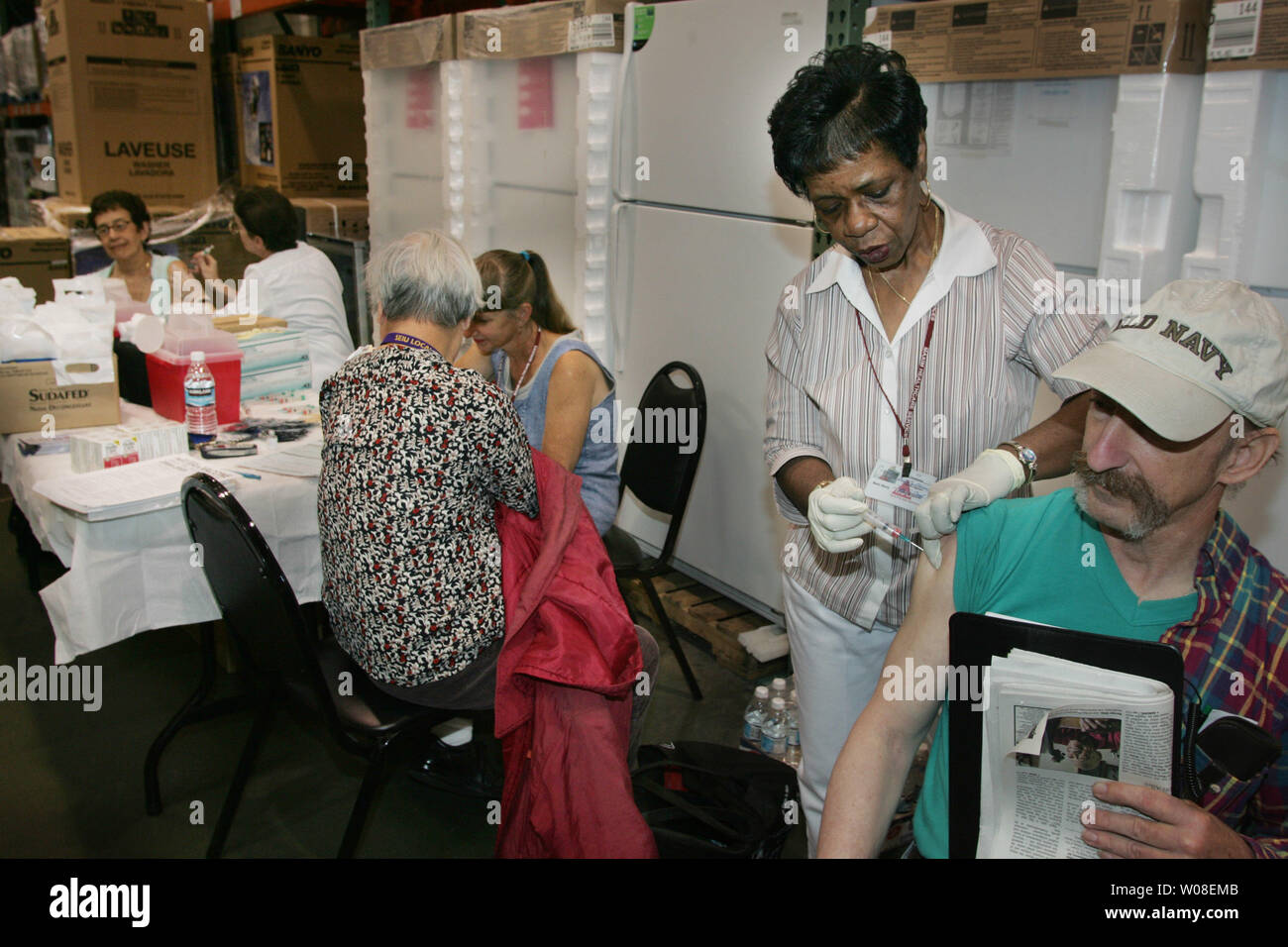 Nurse Betty Davis (R) gibt eine Impfung bei einer Grippeimpfung Klinik bei Costco in San Francisco, CA, das am 13. Oktober 2004 statt. Die Leute begannen, Ankunft um 5 Uhr für die 10:00 Uhr Klinik, die hatte eine geschätzte 400 Dosen. (UPI Foto/Terry Schmitt) Stockfoto