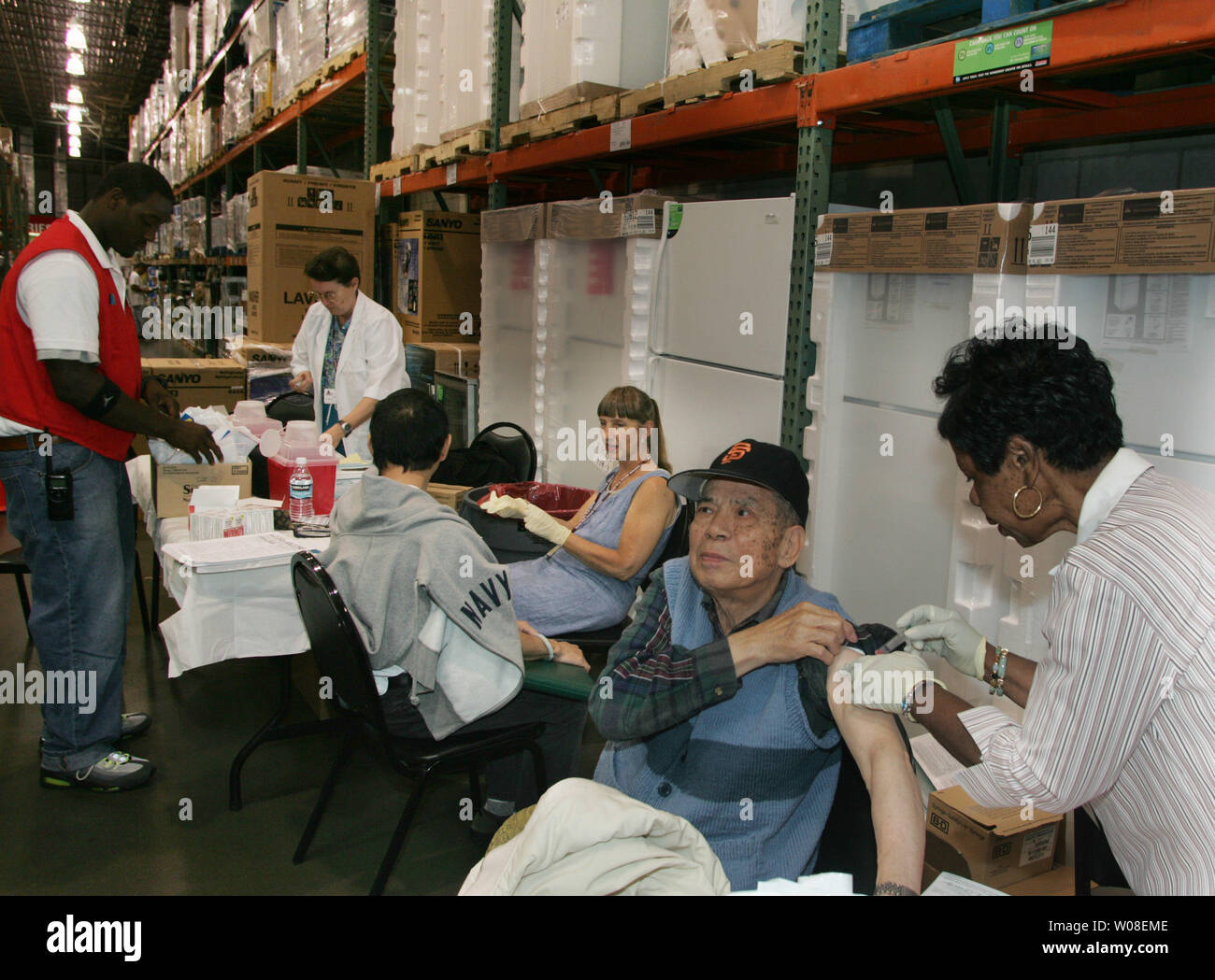 Nurse Betty Davis (R) gibt eine Impfung bei einer Grippeimpfung Klinik bei Costco in San Francisco, CA, das am 13. Oktober 2004 statt. Die Leute begannen, Ankunft um 5 Uhr für die 10:00 Uhr Klinik, die hatte eine geschätzte 400 Dosen. (UPI Foto/Terry Schmitt) Stockfoto