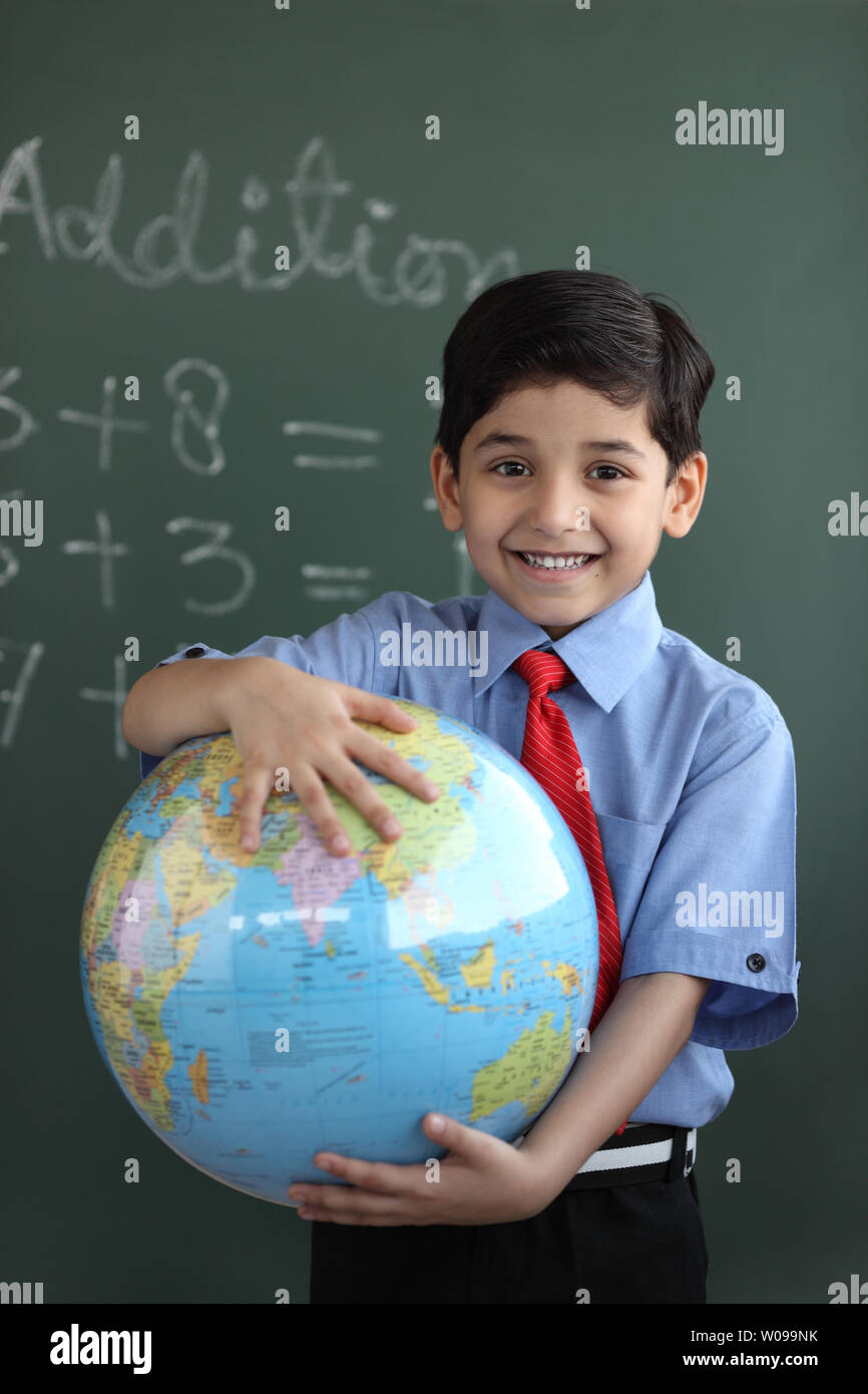 Porträt von Schuljunge hält einen Globus und lächelnd Stockfoto