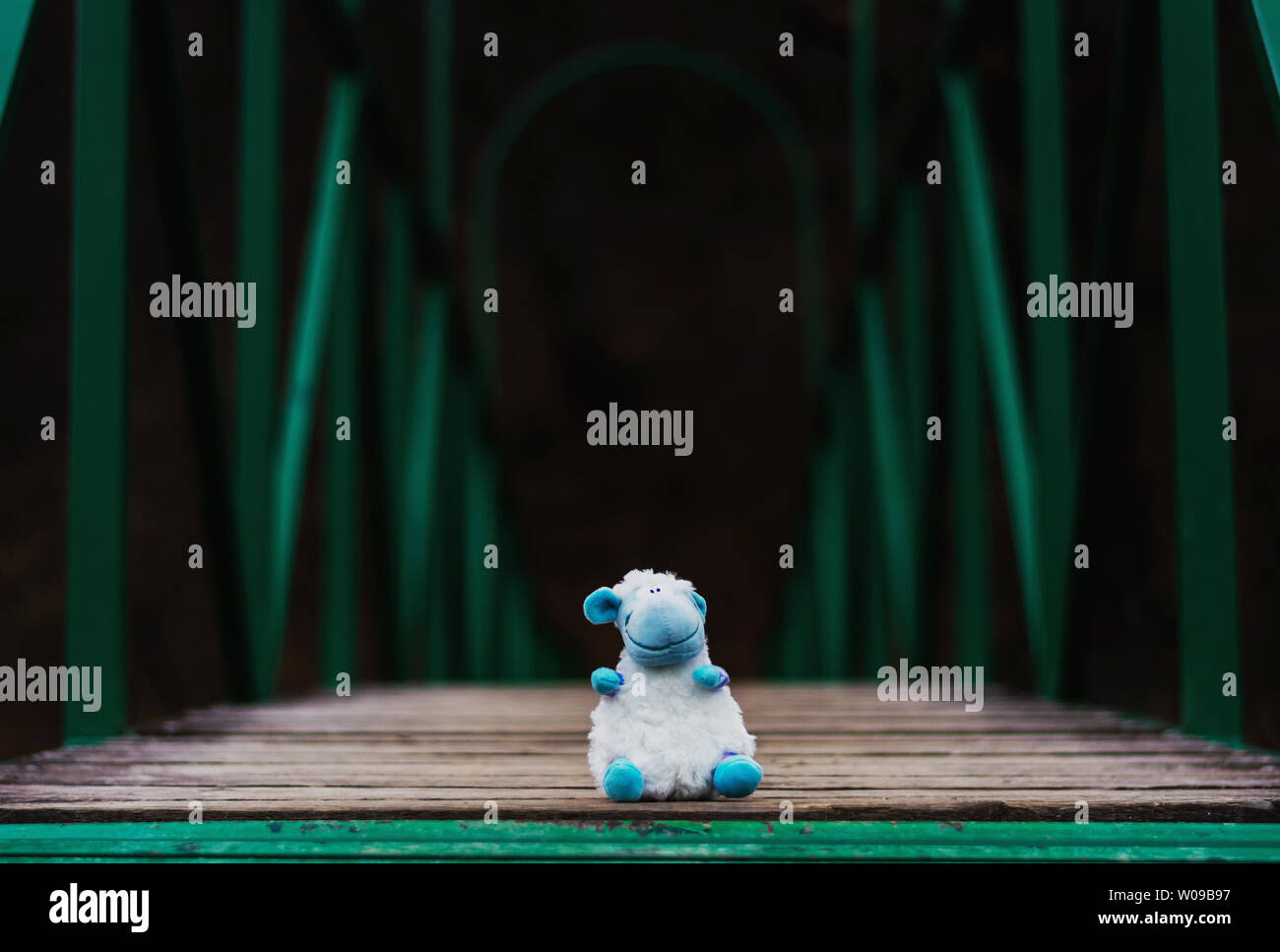 Eine flauschige Schafe auf einer Fußgängerbrücke über einen Stream abgebrochen Stockfoto