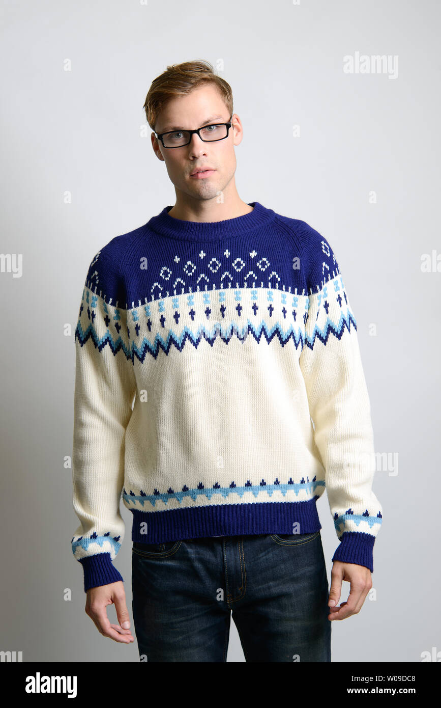 Ein braunes kaukasisches männliches Model posiert im Vintage-Pullover und trägt eine Brille, ein Vintage-Mode-Editorial für Männer. Stockfoto