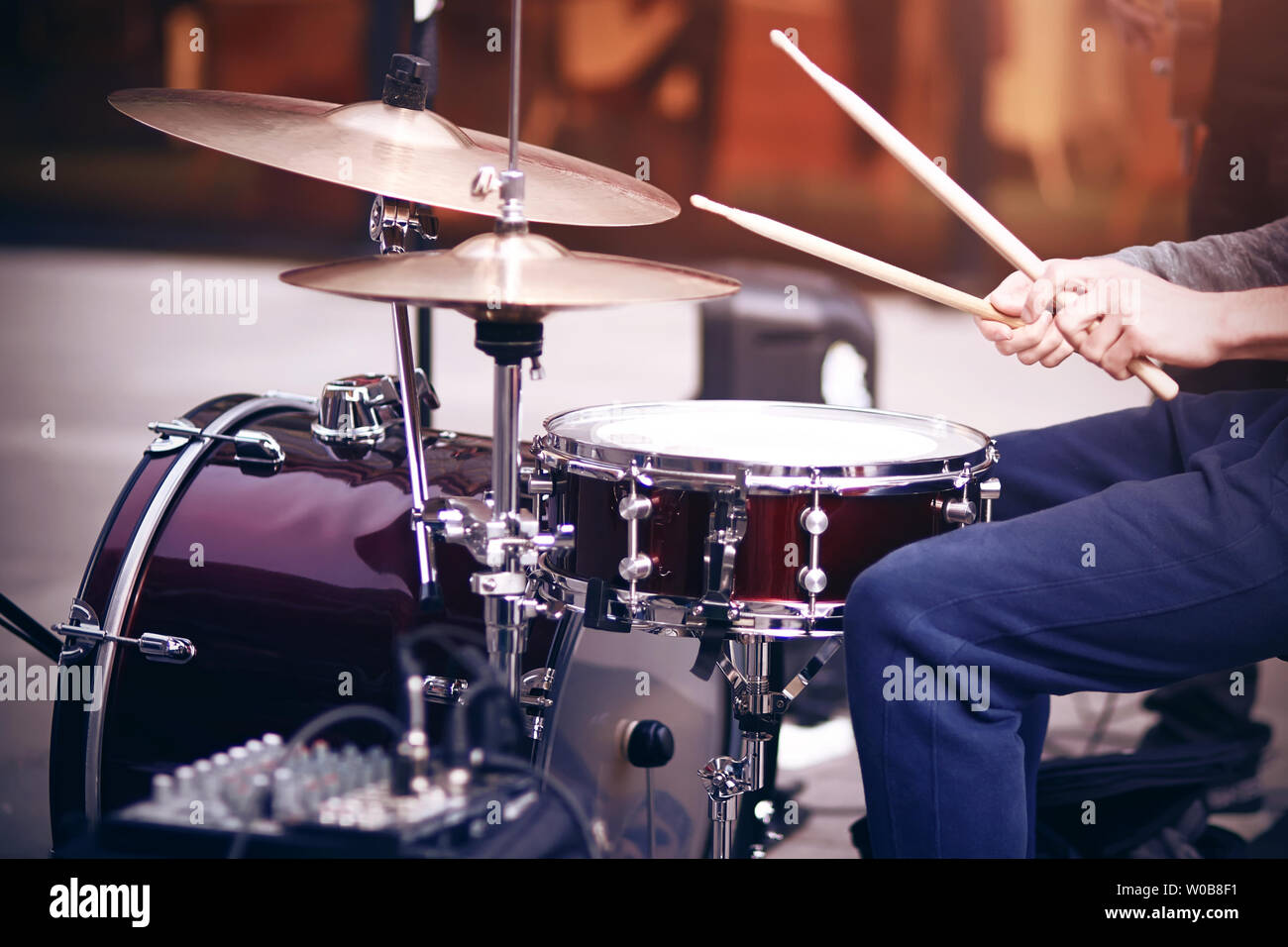 Guy ist ein strassenmusiker in blauen Hosen Rhythmus spielen auf einem schönen roten Drum mit hölzernen Trommelstöcke eingestellt Stockfoto