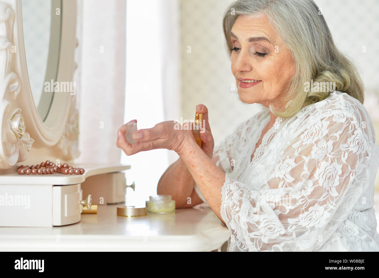 Portrait von Schöne ältere Frau, die Sahne und zu Hause posieren Stockfoto
