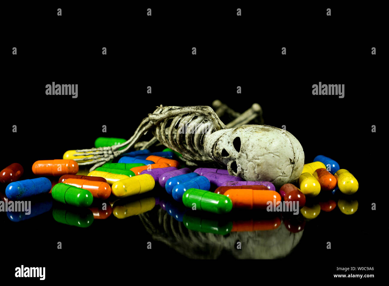 Menschliche wie Gummi Skelett Verlegung auf farbigen Pillen, konzeptionelle Bild über Krankheit, Tod und pharmazeutische Industrie Stockfoto