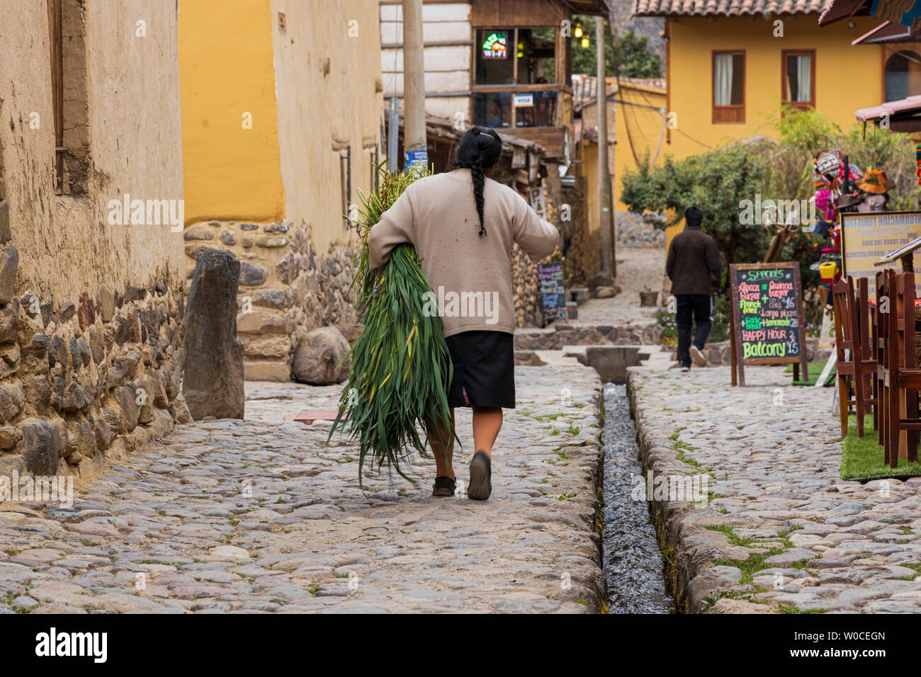 Indigene Frau, die geschnittene Pflanzen, Blätter, auf einem gepflasterten Straßen in Cusco, Sacred Valley, Peru, Südamerika Stockfoto