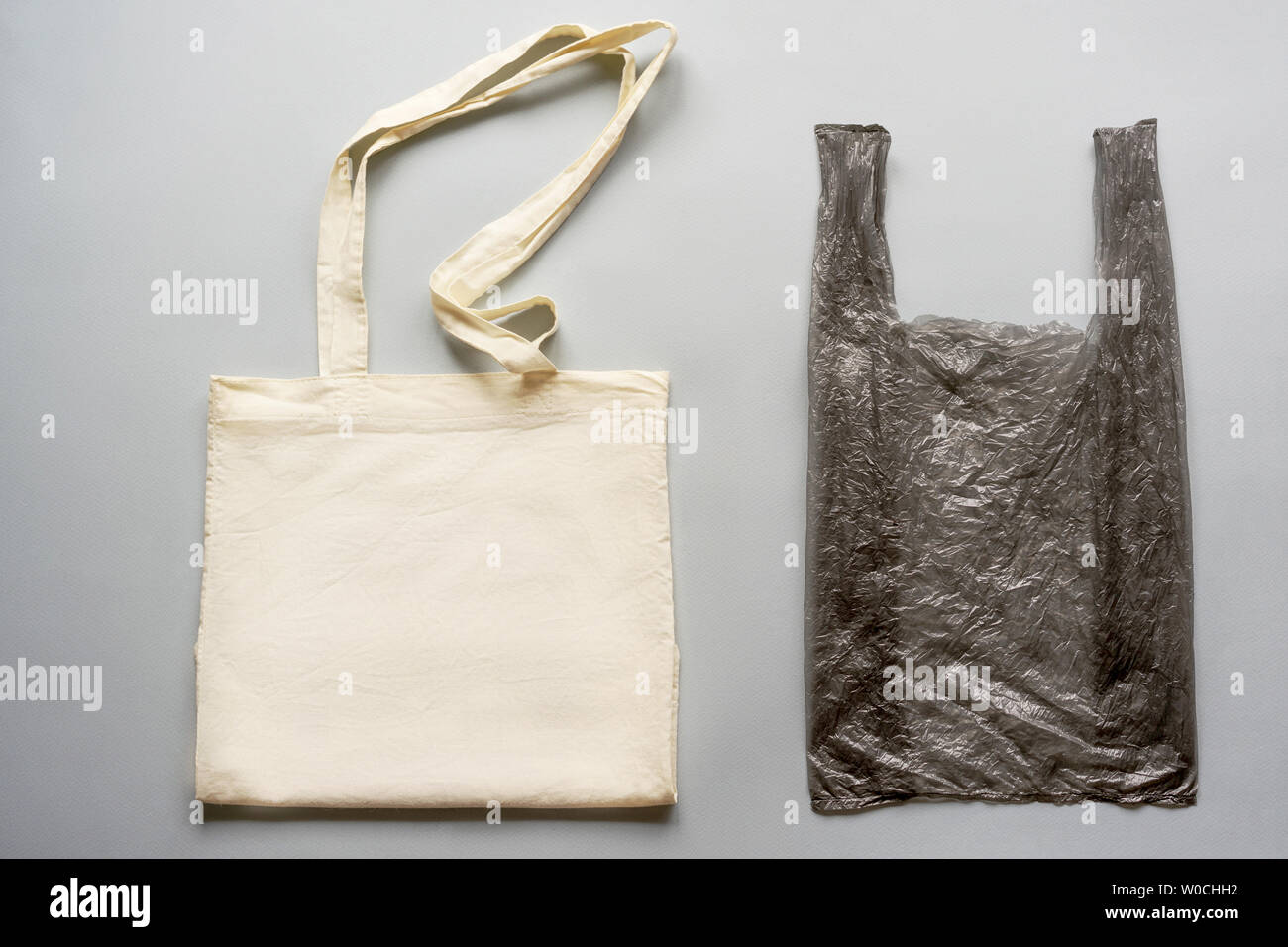 Auf die graue Ebene sind ein weißer Baumwolle Tasche und einem schwarzen wiederverwendbare Tasche. Ökologische Konzept des täglichen intelligente Wahl einer fortschrittlichen Gesellschaft. Stockfoto