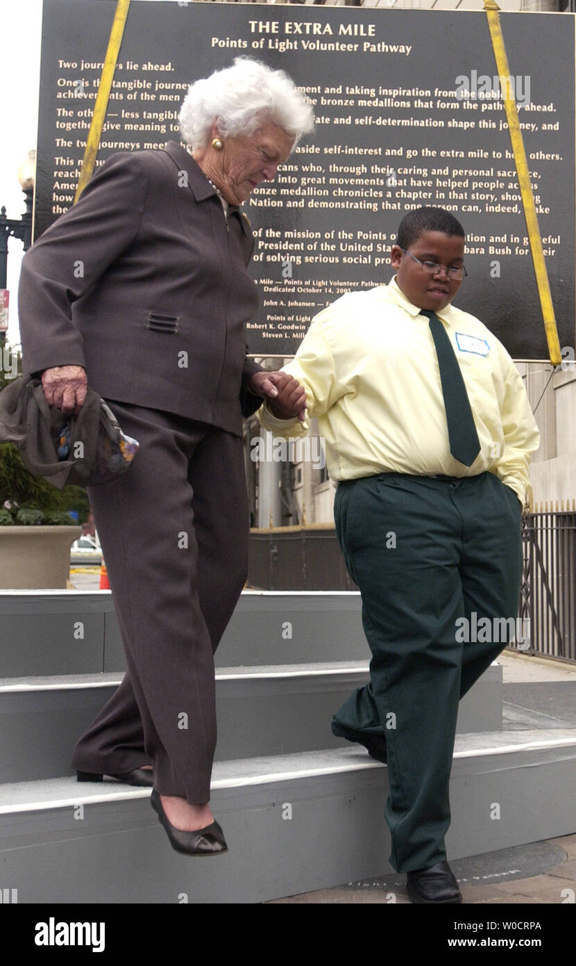 Ehemalige First Lady Barbara Bush ist von der Bühne durch Cortez Malone an die Extra Meile denkmal Enthüllung geholfen, einen 1,6 km langen Spaziergang in der Innenstadt von Nordwesten besetzt mit Bronze Medaillons ehrt 70 Amerikaner, die ihr Leben dem Dienst an den Mitmenschen, in Washington am Okt. 14, 2005. (UPI Foto/Kevin Dietsch) Stockfoto