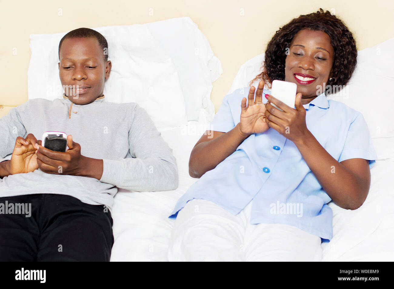 Dieses junge Paar gerne jedes Mobiltelefon im Bett zu übernehmen Stockfoto