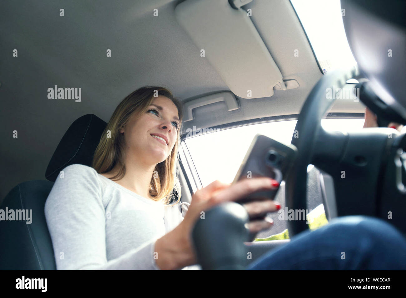 Junge Frau mit Smartphones in Ihrem Auto Stockfoto