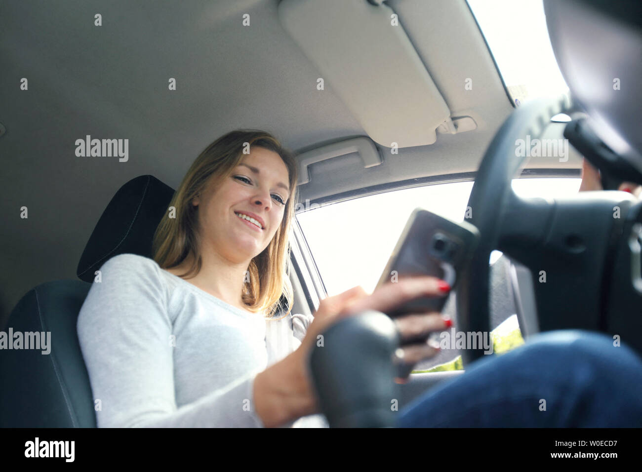 Junge Frau mit Smartphones in Ihrem Auto Stockfoto