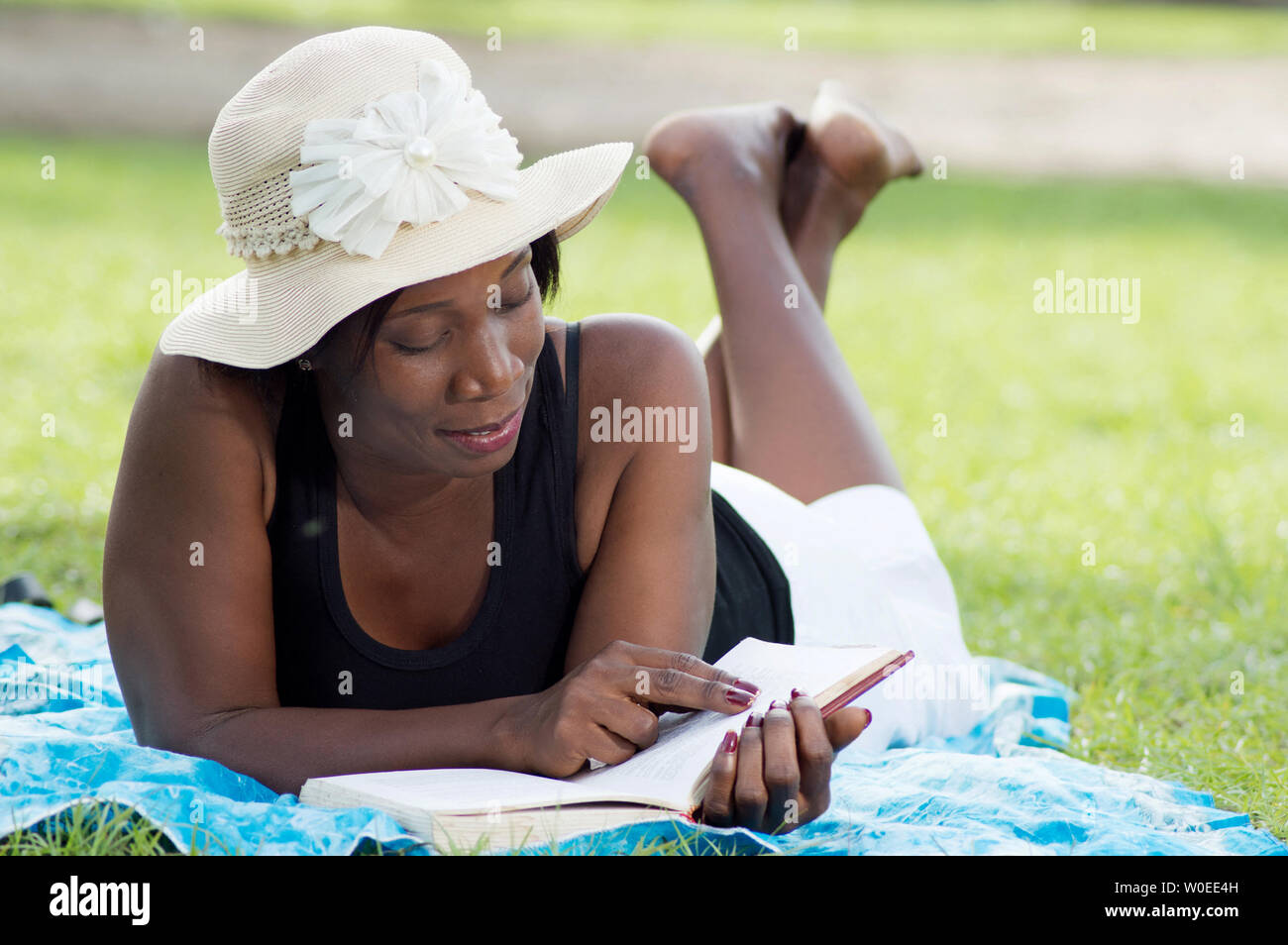 Diese junge Frau liegen im Schatten eines Baumes ist ruhig lesen. Stockfoto