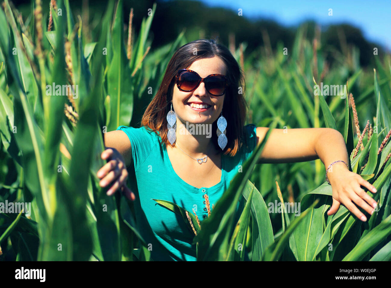 Junge Frau lächelnd in einem Maisfeld Stockfoto