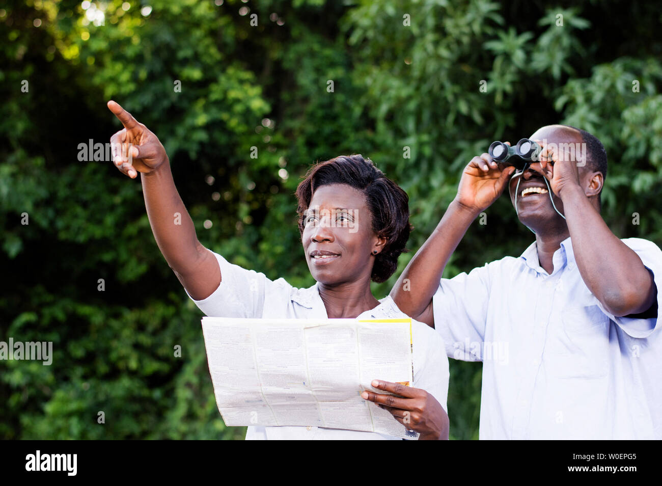 Junge Frau auf etwas, was der junge Mann schaut durch ein Fernglas zeigt. Stockfoto