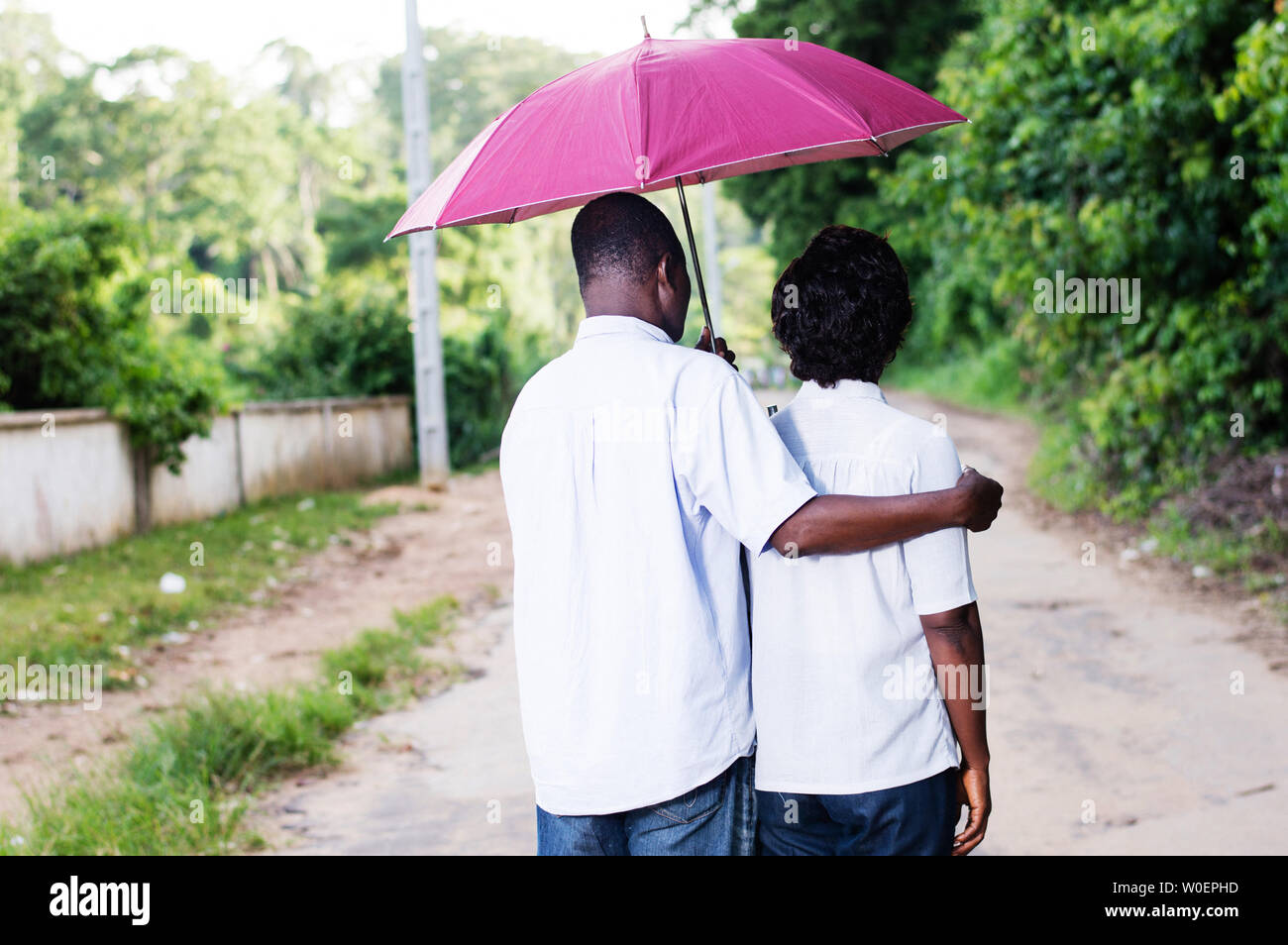 Junge Paare schlendern und durch einen Regenschirm abgedeckt. Stockfoto