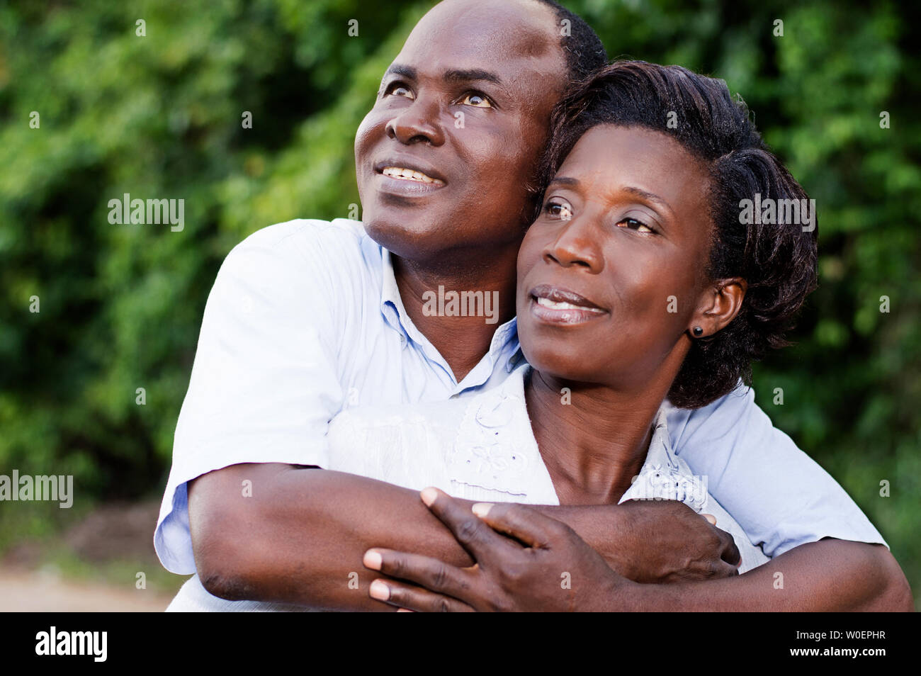 Glückliches junges Paar umarmen schauen etwas auf Baum. Stockfoto