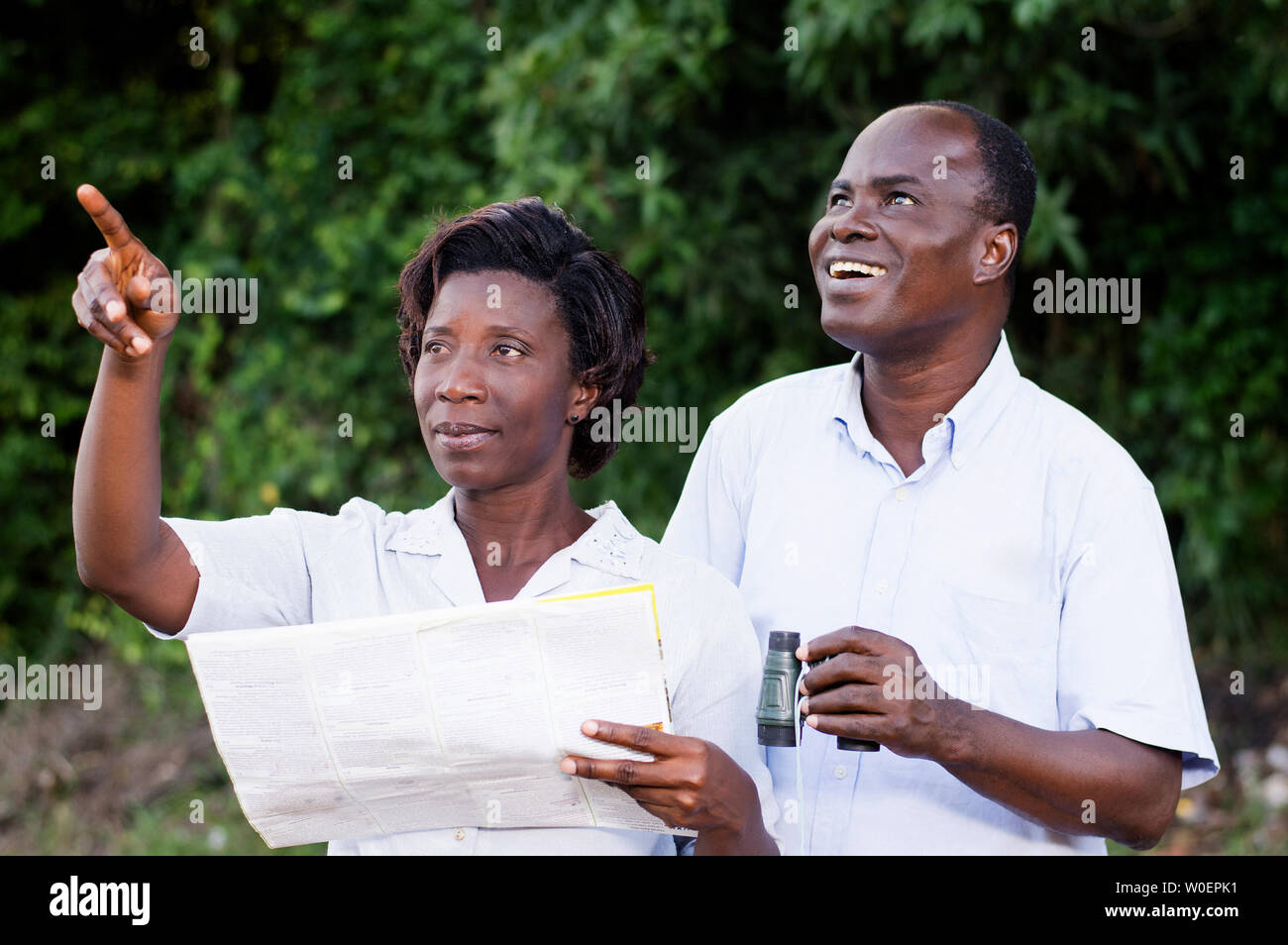 Junge Frau auf etwas, was der junge Mann schaut durch ein Fernglas zeigt. Stockfoto