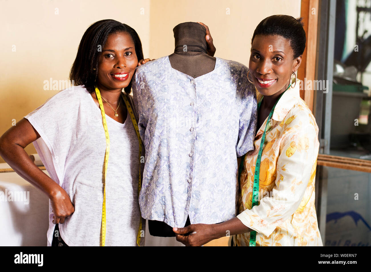 Zwei lächelnde Näherinnen neben einer Schaufensterpuppe in Ihrem Studio. Stockfoto