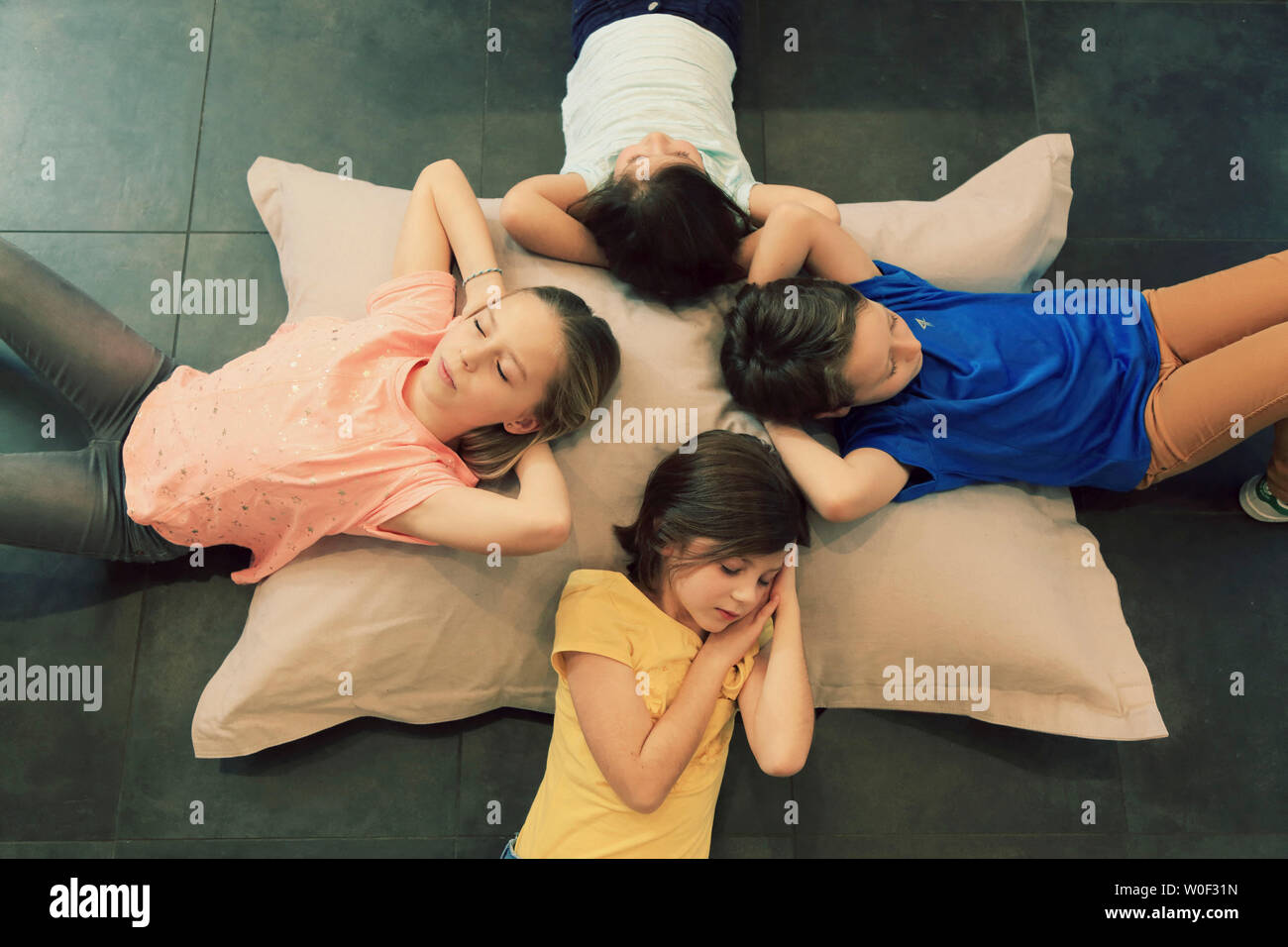 Vier Kinder schlafen auf einem grossen Kissen Stockfoto