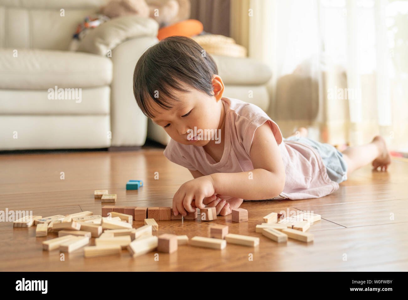 Baby liegend auf dem Holzboden spielen Bausteine Stockfoto