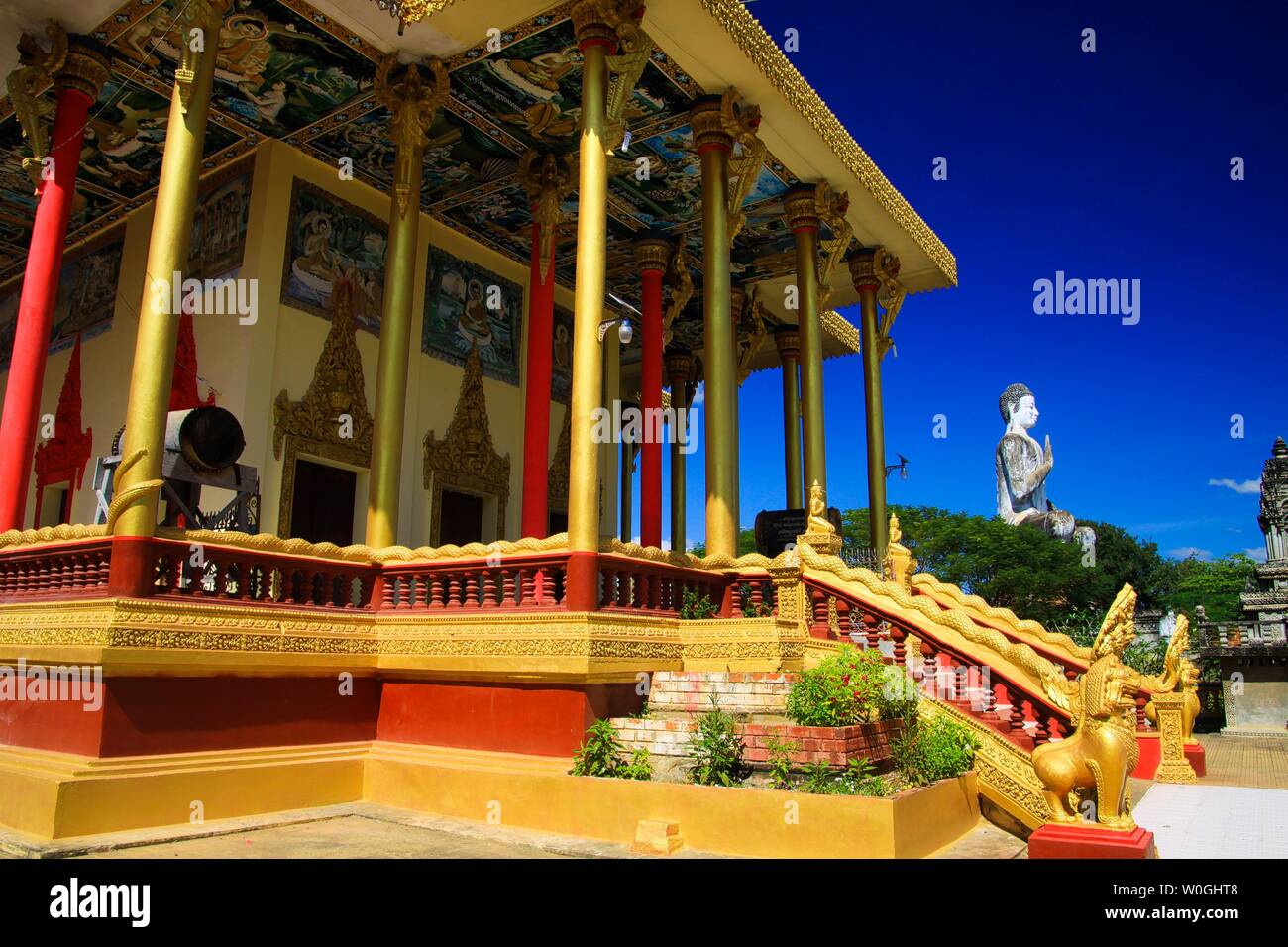 Blick auf goldenen Säulen, Trommel und weißen Buddha Statue gegen den blauen Himmel in buddhistischen Tempel - Wat Ek Phnom, in der Nähe von Battambang, Kambodscha Stockfoto