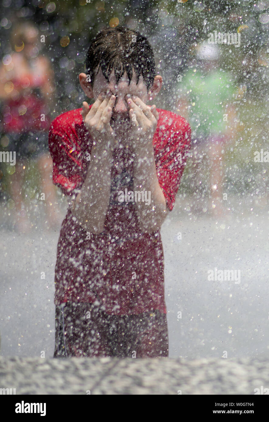 Ein Junge versucht zu schlagen, um die Wärme, wie Er kühlt sich in einem Brunnen an der Georgetown Waterfront am 29. Juni 2012 in Washington, D.C. Temperaturen erwartet werden rund 100 Grad durch das Wochenende zu schweben. UPI/Kevin Dietsch Stockfoto