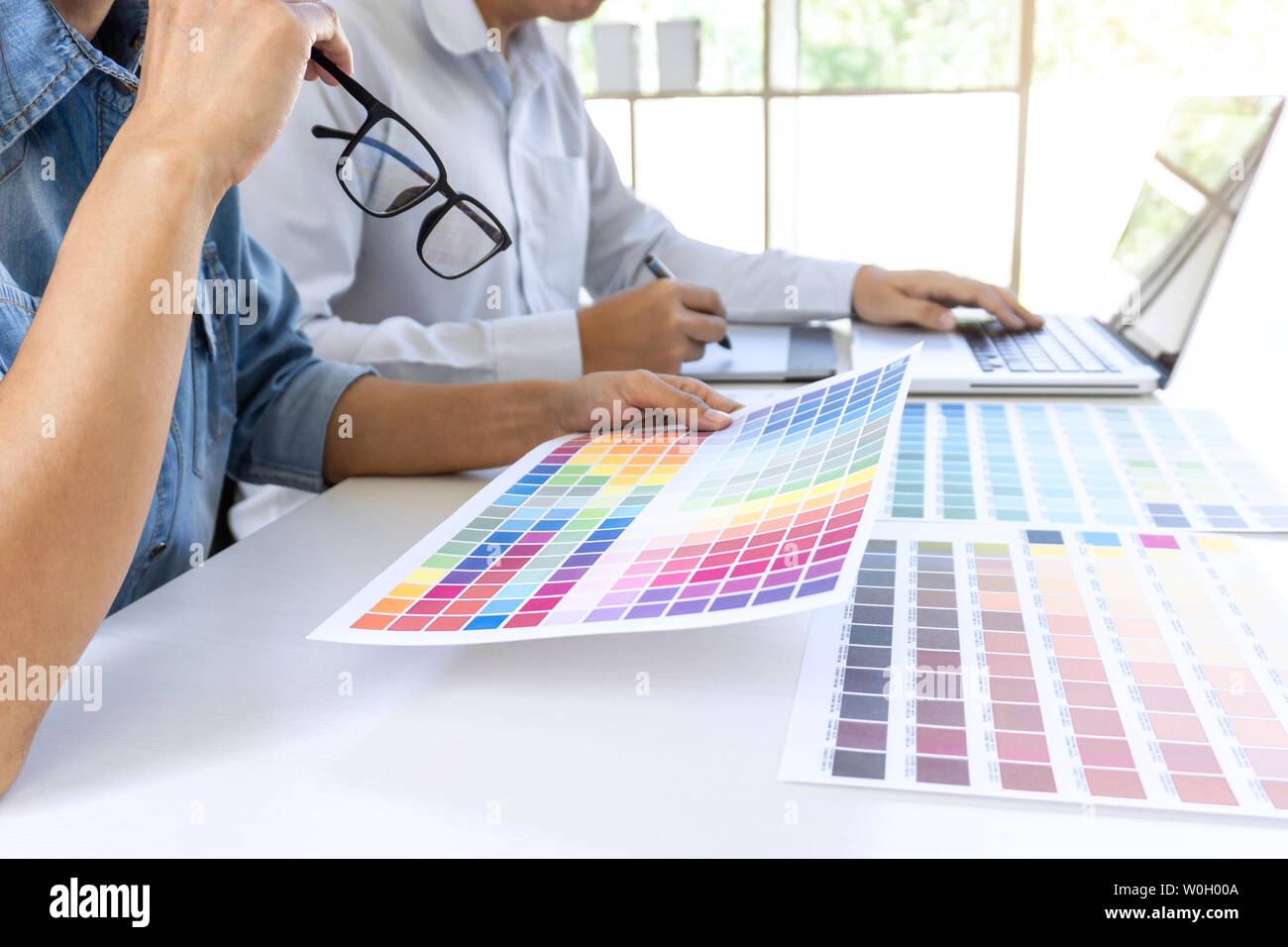 Team von Kollegen Grafiker zeichnen und retuschieren Bild auf dem Grafiktablett und wählen Sie Farbe swatch Proben für die Auswahl auf einem Laptop. Stockfoto